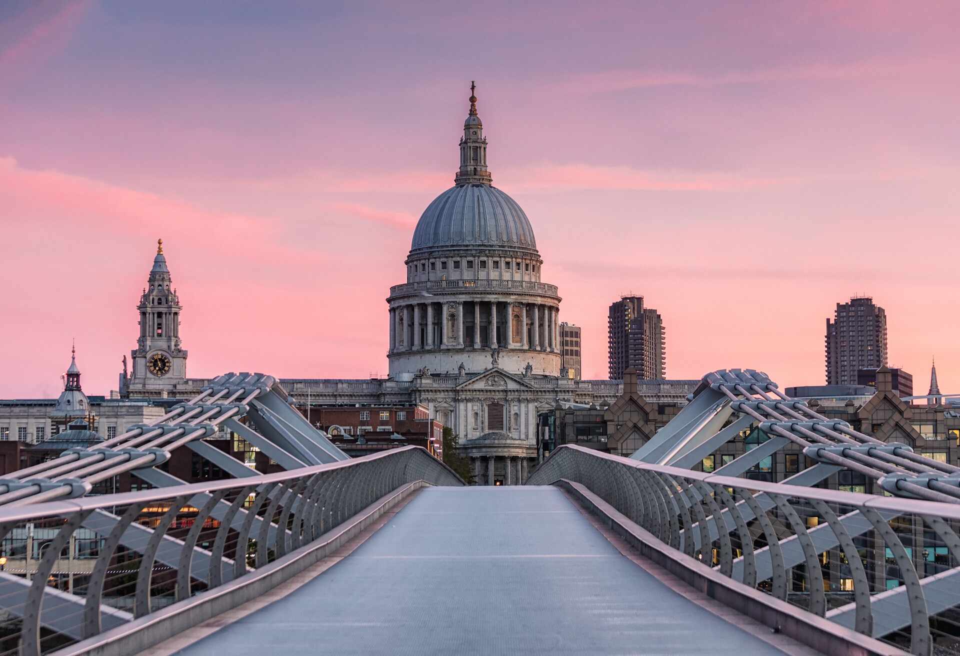 Millennium Bridge, London, UK. October 7, 2018. An early morning view of St Paul's Cathedral from the Millennium Bridge, London. The sky glows pink from the rising sun.