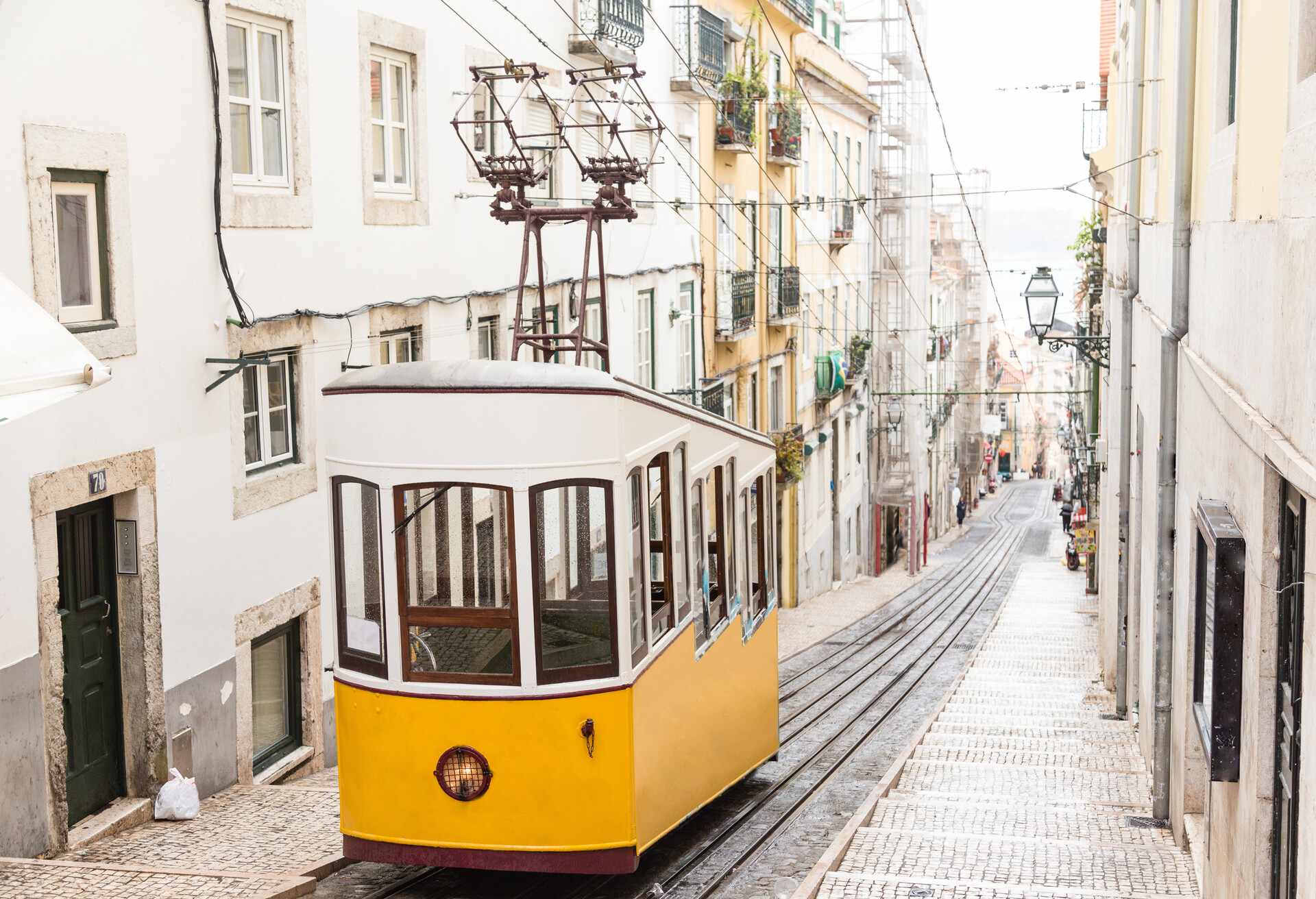 Typical yellow old tram funicular Elevador da Bica in Bairro Alto, going up hill in the old town of Lisbon
