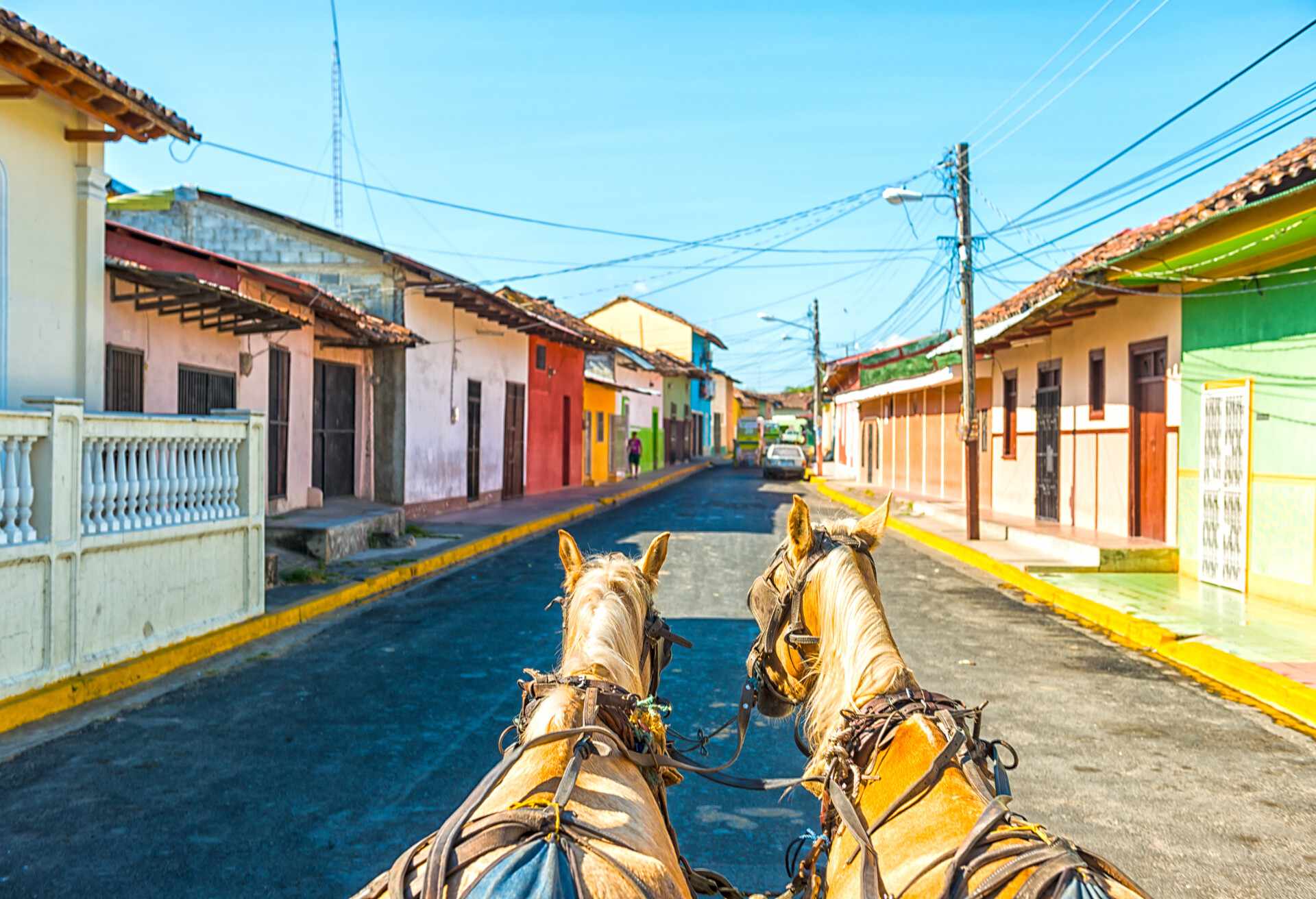 Site seeing by horse carriage the old city Granada in Nicaragua. Colorful facades against blue sky.