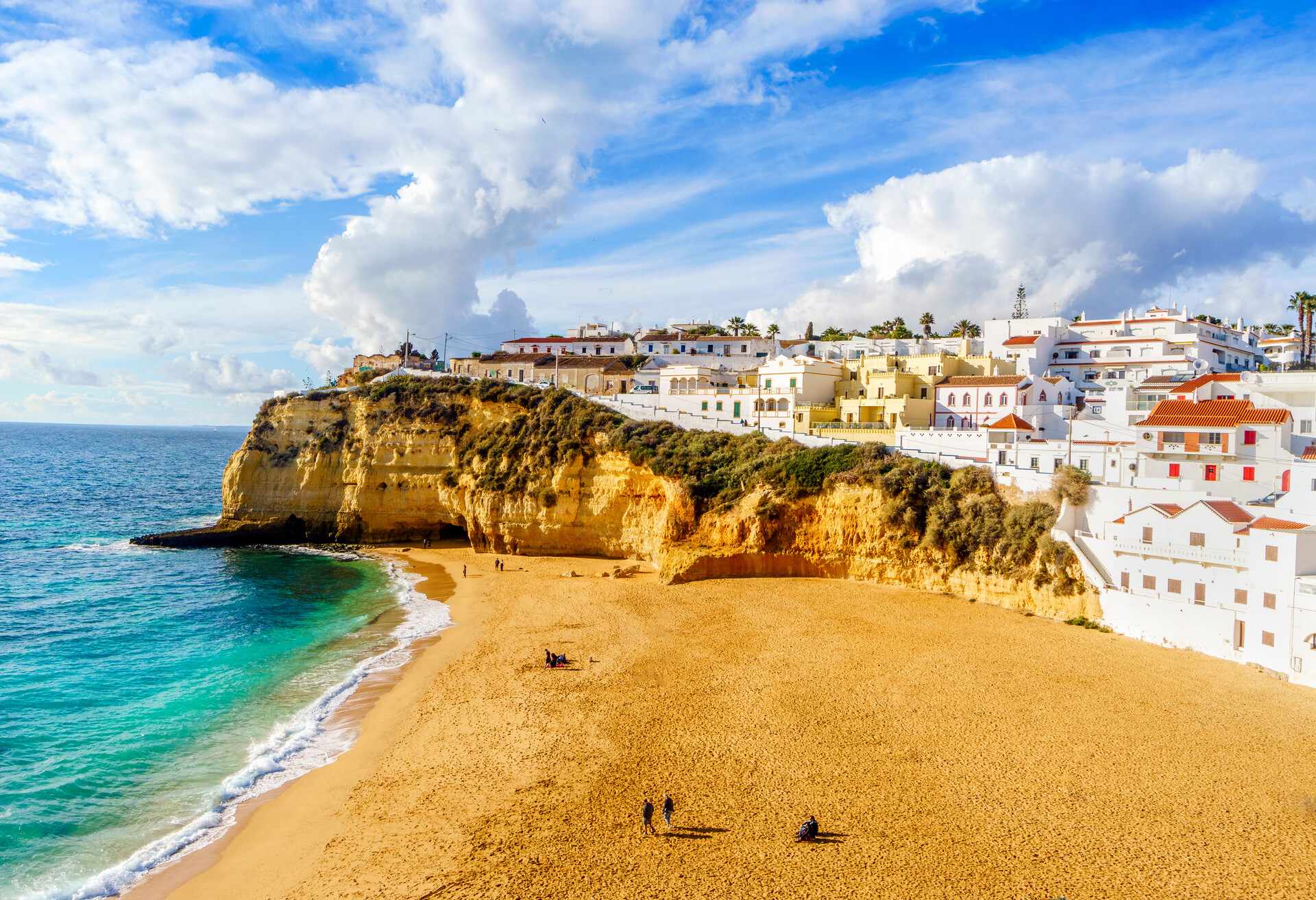 Wide sandy beach between cliffs and in front of charming white architecture in Carvoeiro, Algarve, Portugal