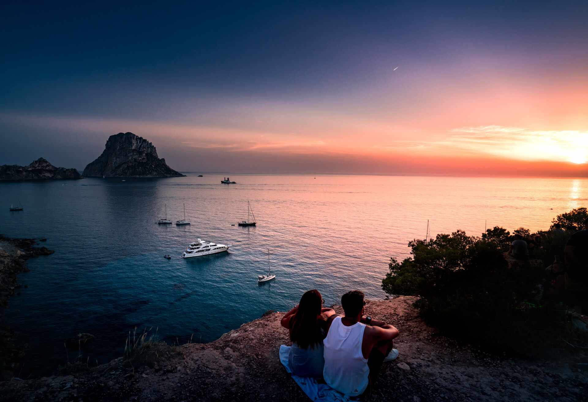 Woman and man back to the front watching a beautiful sunset at the beach. The beach is called Es Vedra, in Ibiza and belongs to balearic islands, in Spain