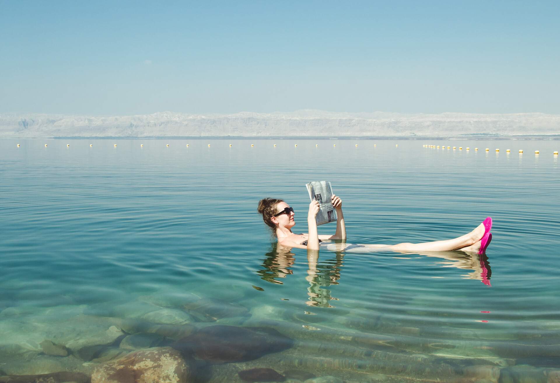 Photo of the Girl reading newspaper floating on surface Dead Sea enjoy summer sun and vacation. Recreation tourism, healthy lifestyle, free time concept; Shutterstock ID 500854195; Purpose: Archives; Brand (KAYAK, Momondo, Any): Any