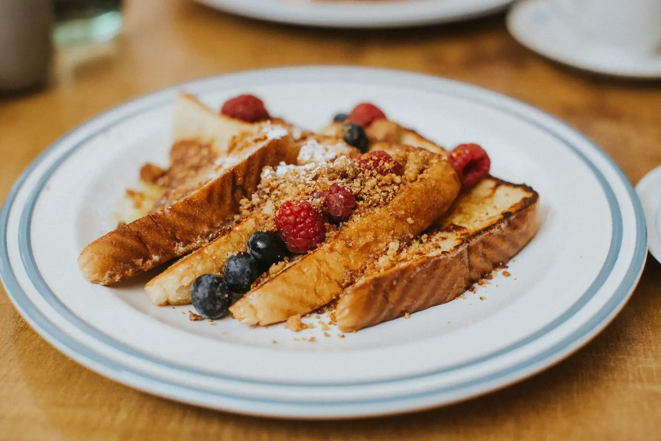 white plate with slices of french toast and berries