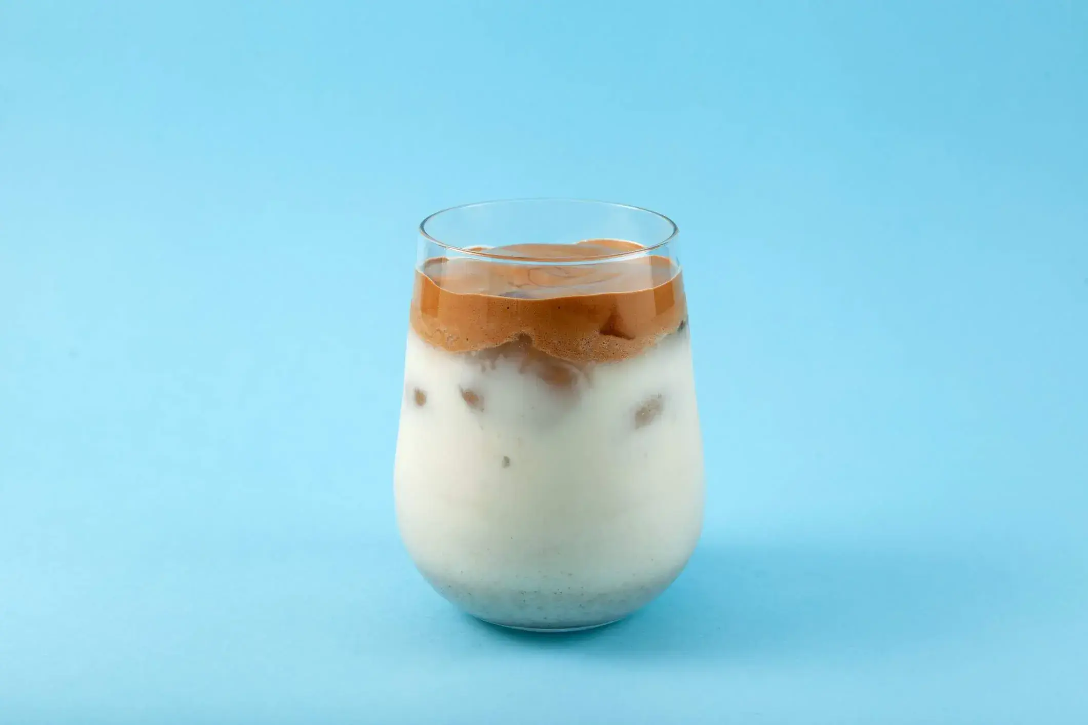glass with milo and milk in front of a blue background