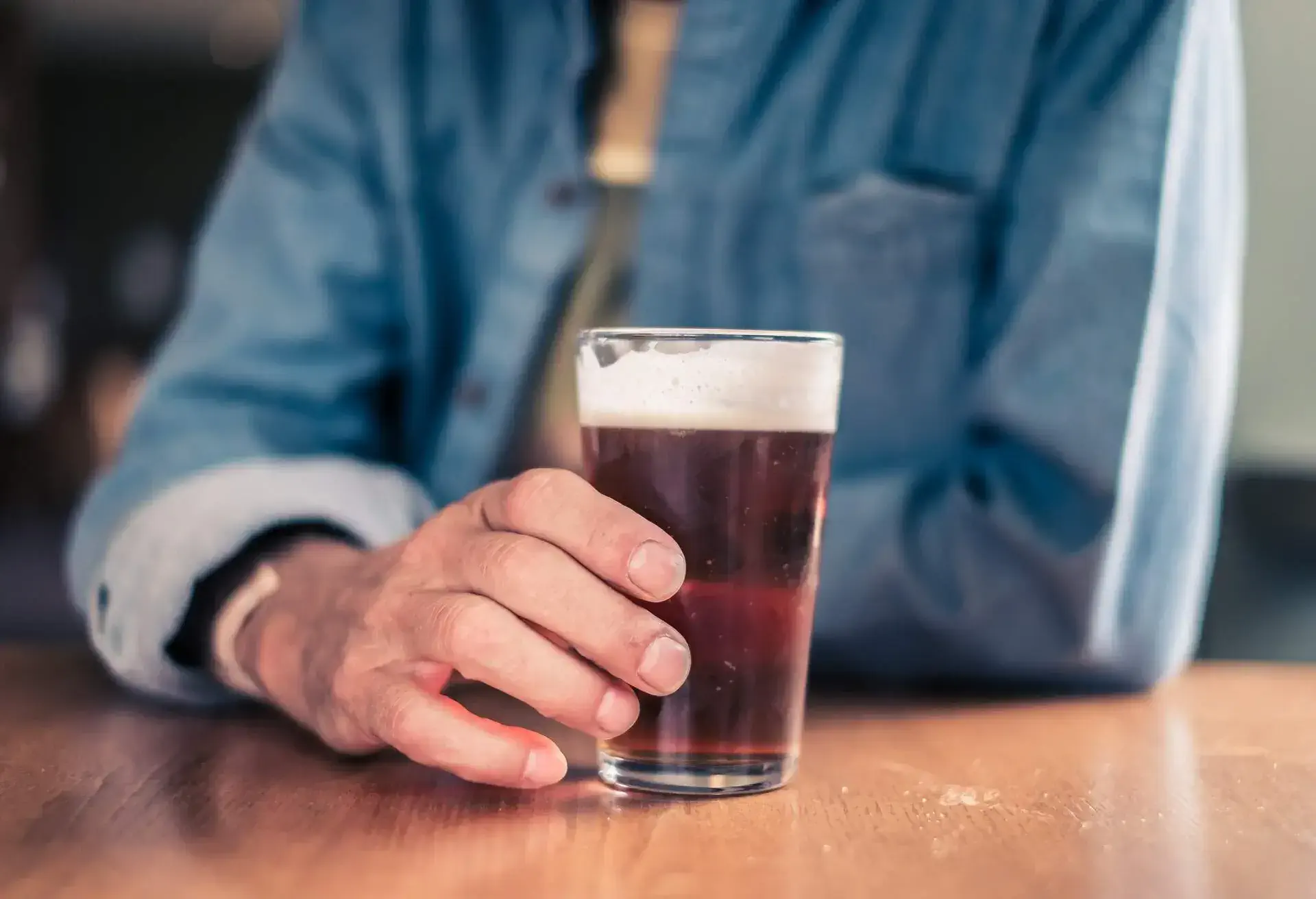 A man holding a beer on a wooden table