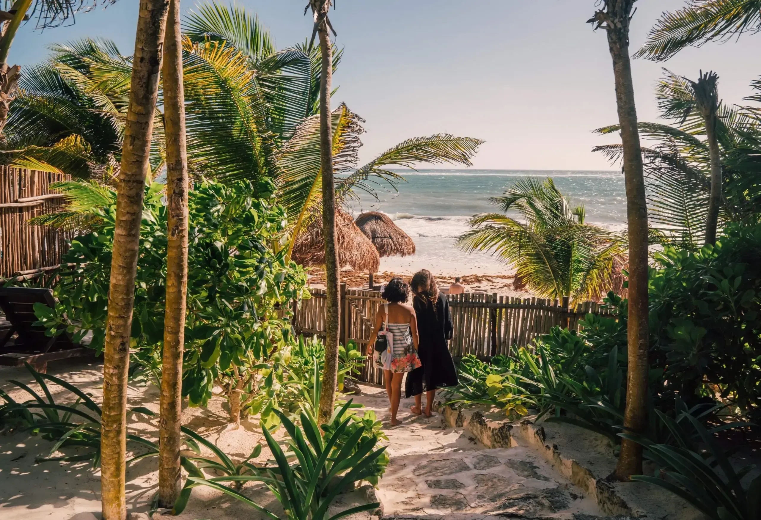 Mother and daughter at tropical beach resort looking at the sea in Tulum, Mexico