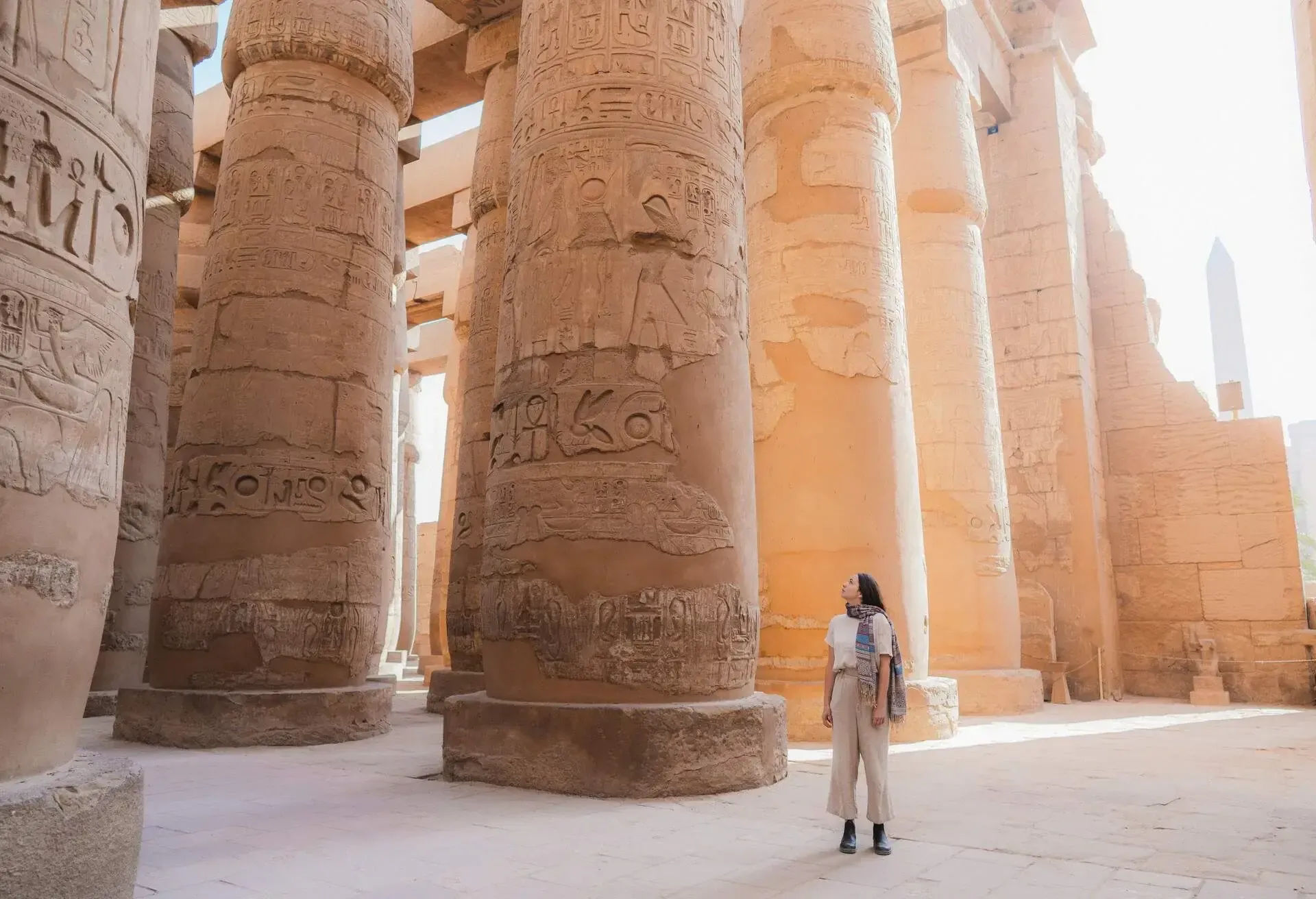 Female traveller standing by ancient Egyptian archeological site made up of column with hieroglyphics