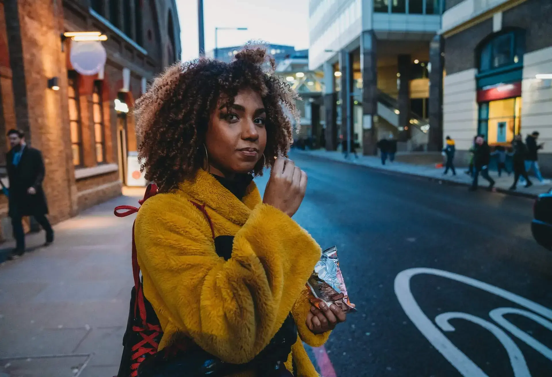 Woman in a yellow coat eating chips from a bag in Canada