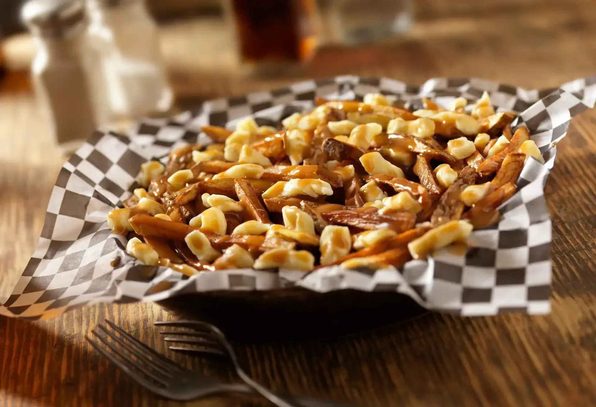 Poutine on a black and white checkered paper on a wooden table