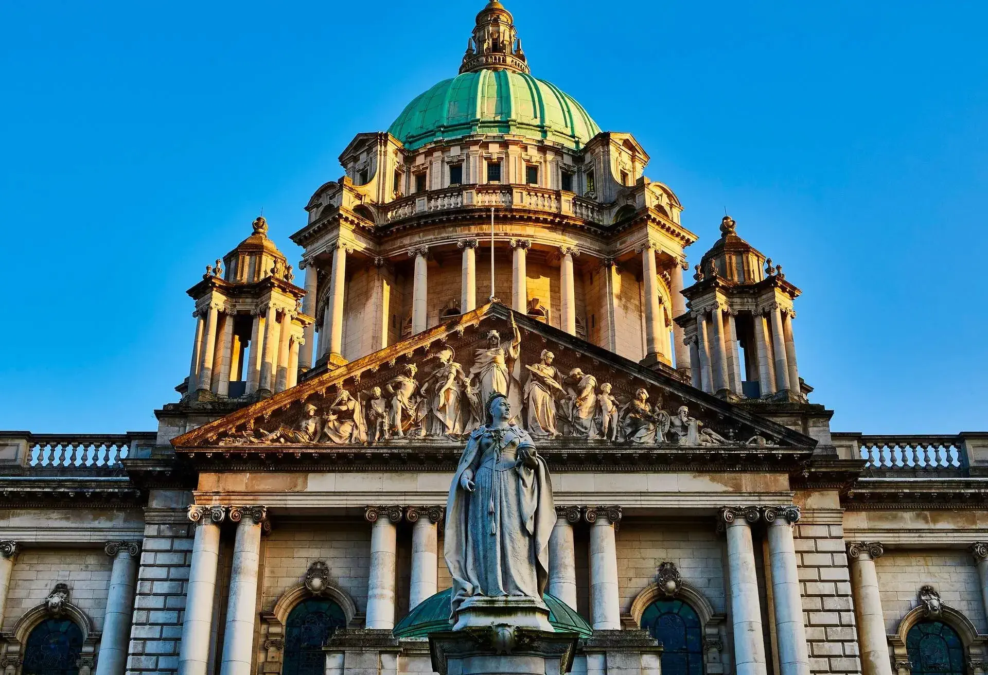 An elegant Baroque Revival civic building adorned with large columns, pediments, statues, sculptures and towers topped with domes.