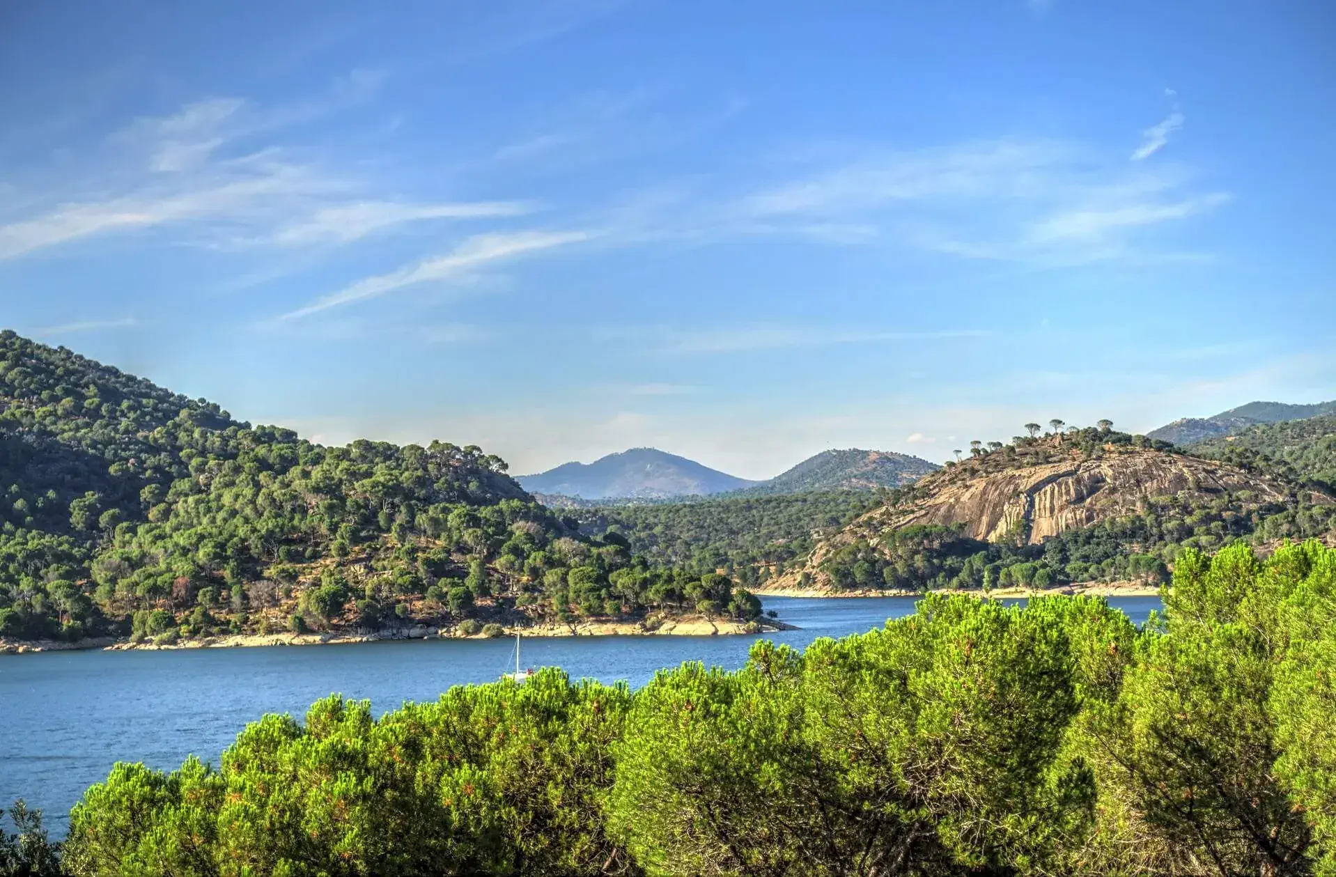 A big, tranquil lake is surrounded by verdant hills.
