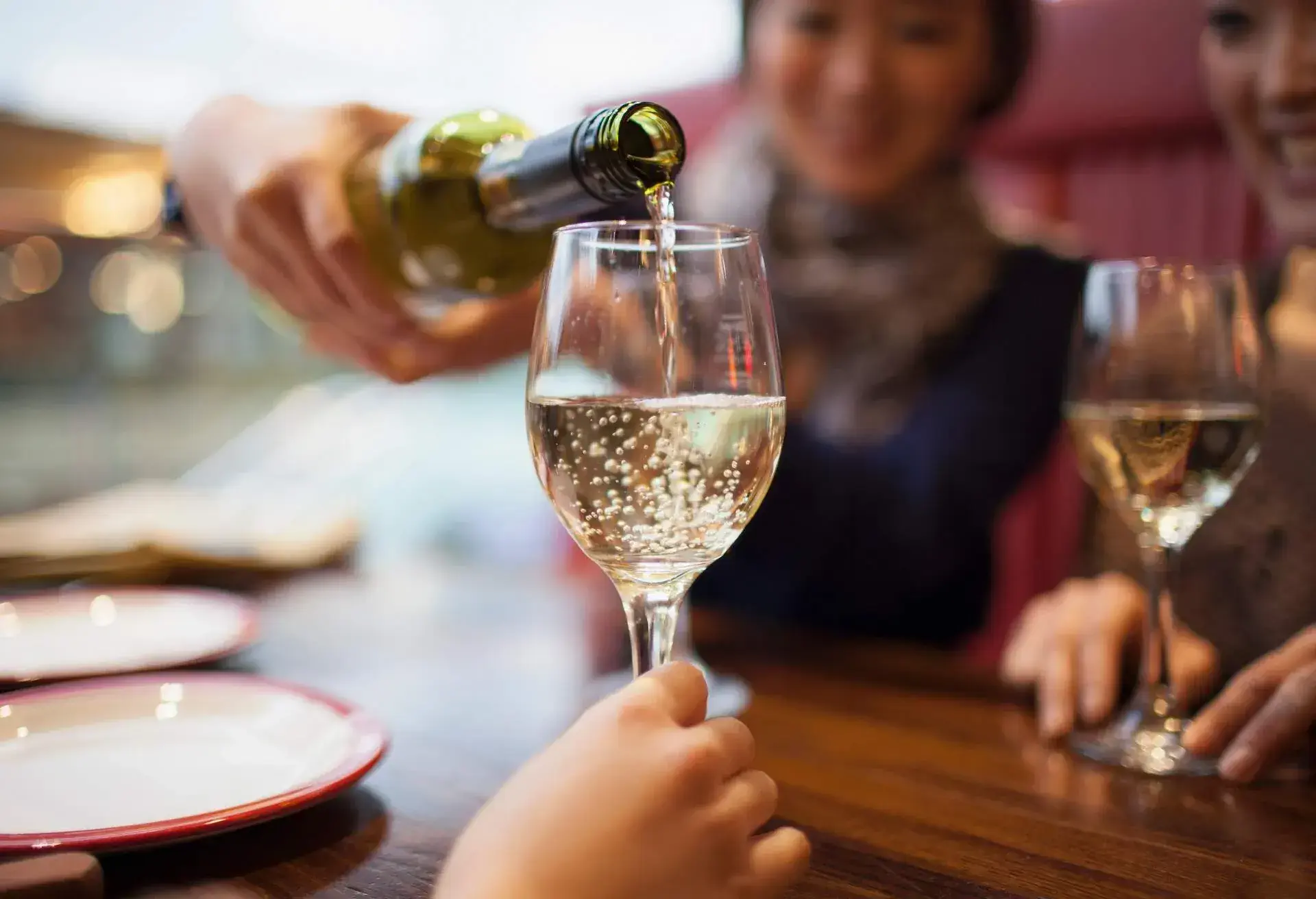 woman serving white sparkling wine in a glass