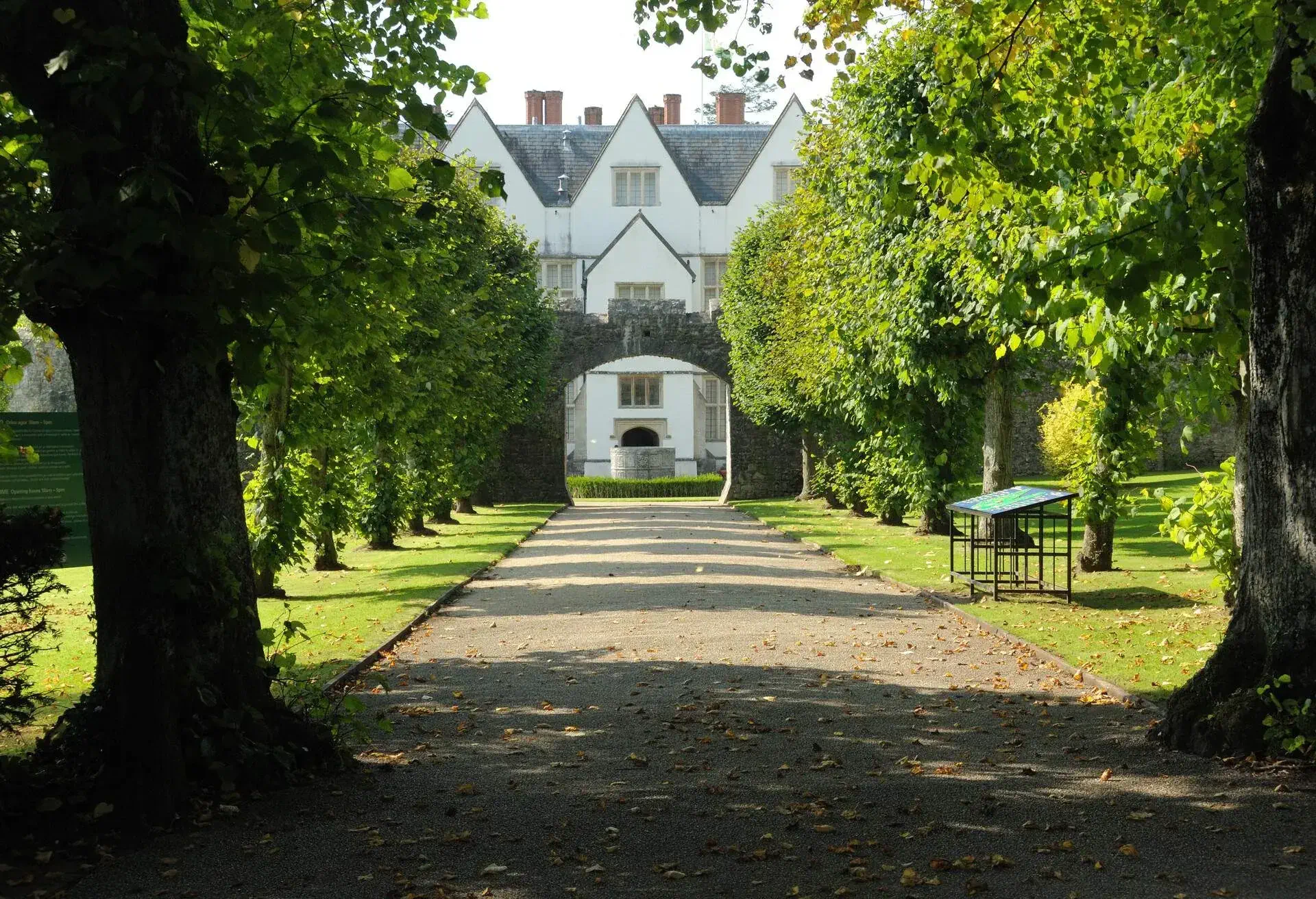 A path in between some trees with a beautiful old building at the end