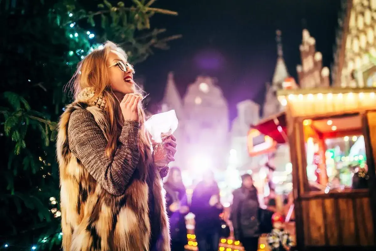 Young woman eating a sweet treat at a Christmas market in France