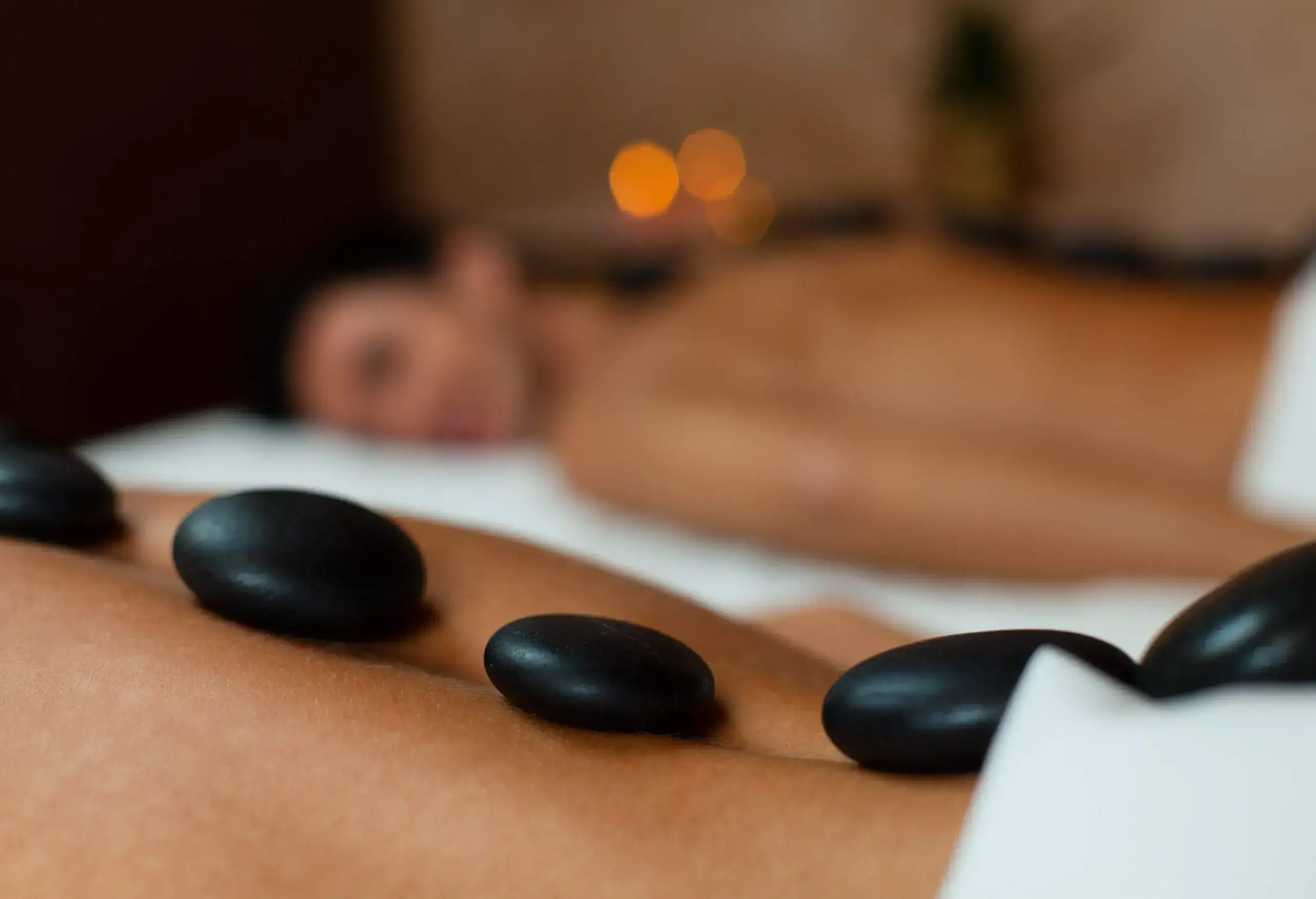 Close-up view of warm stones on woman's back. Couple having lastone massage.