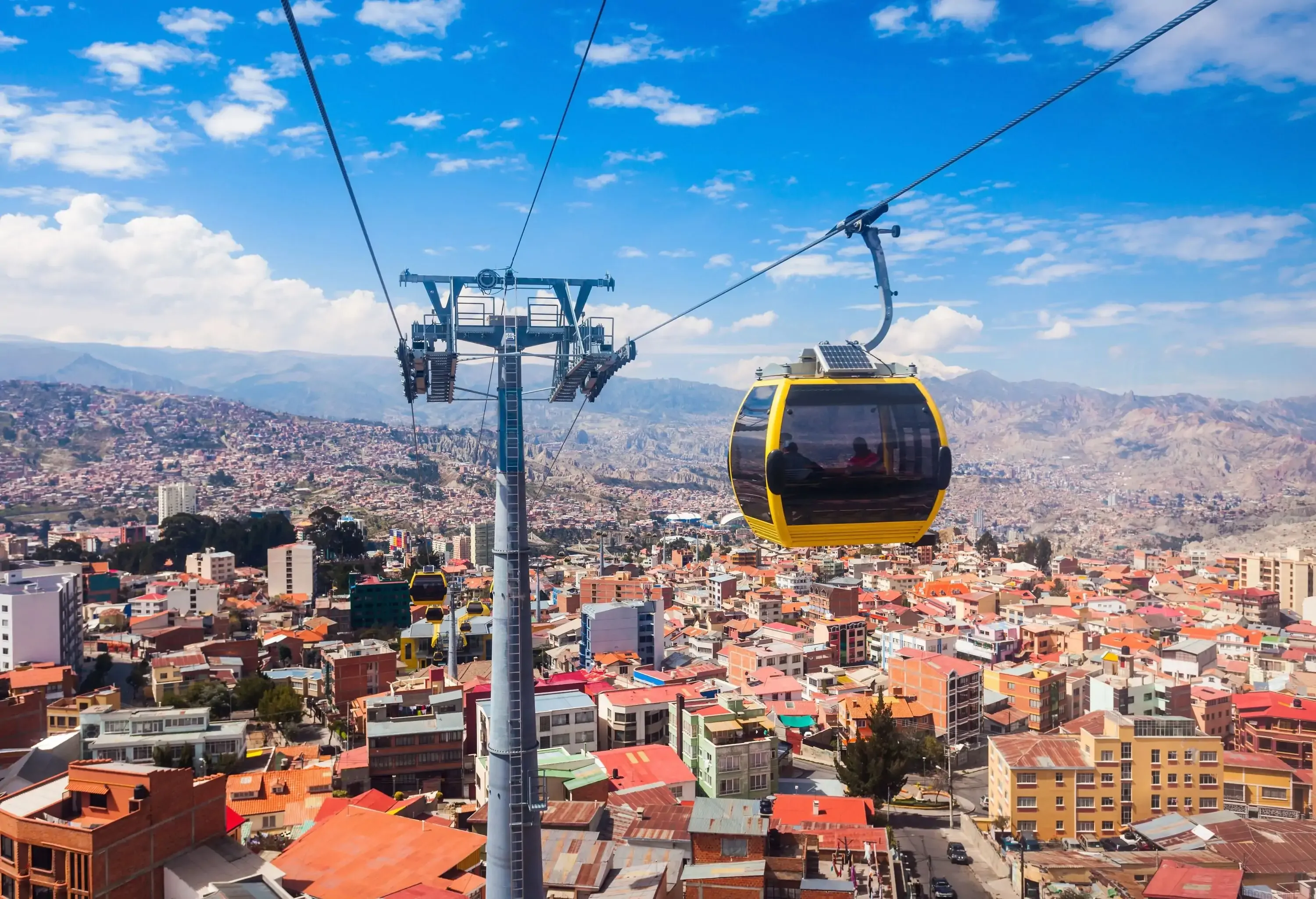 Cable cars travelling above the roofs of compact houses in a populous city.