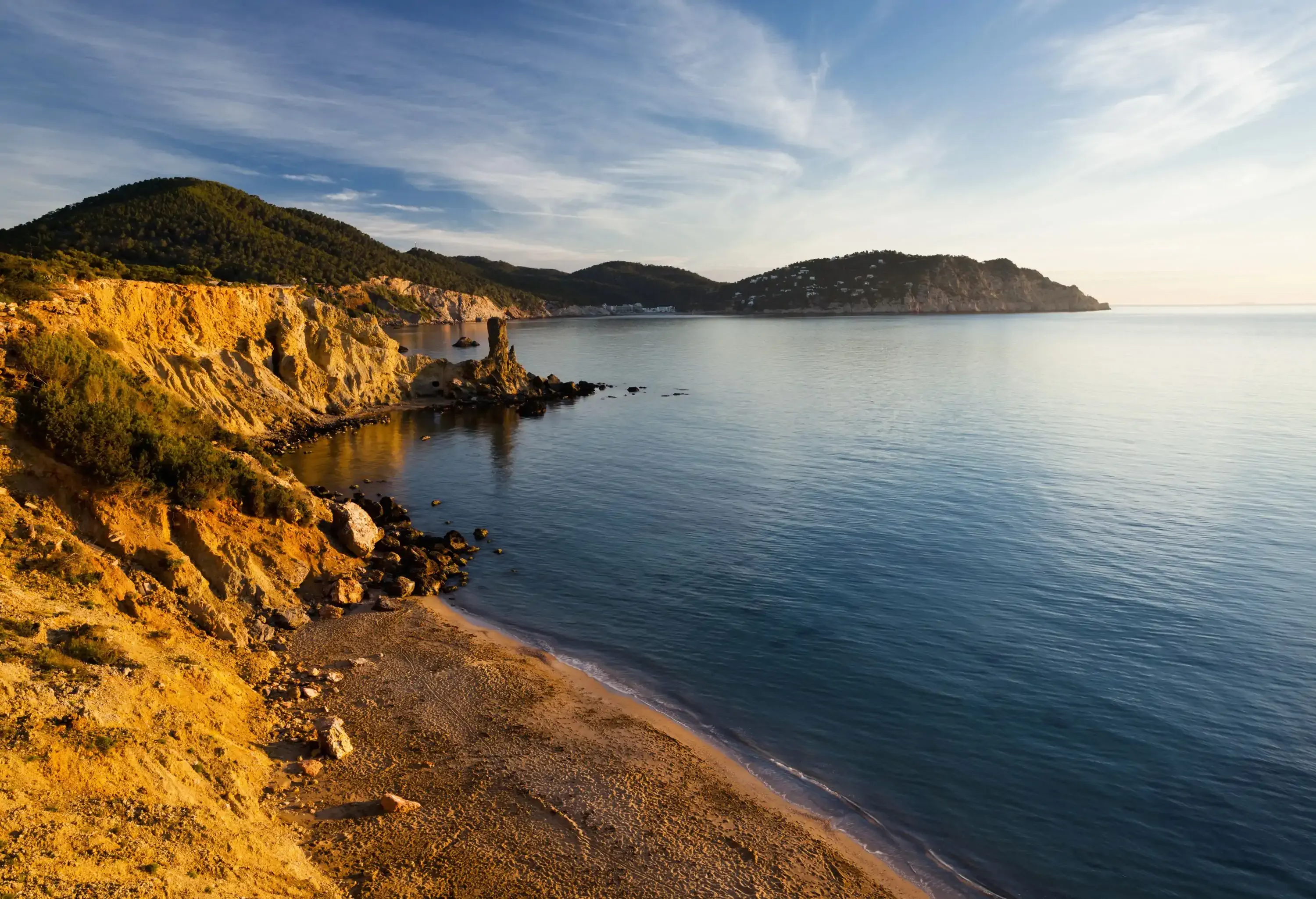 A beach with calm waves along the coastline cliffs.