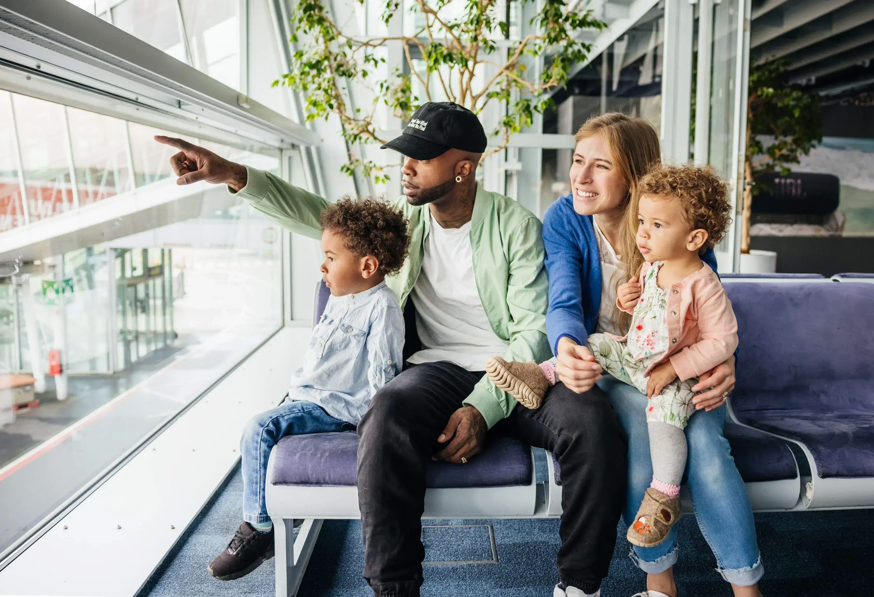 A family waiting at the airport to board their flight, watching planes take off.