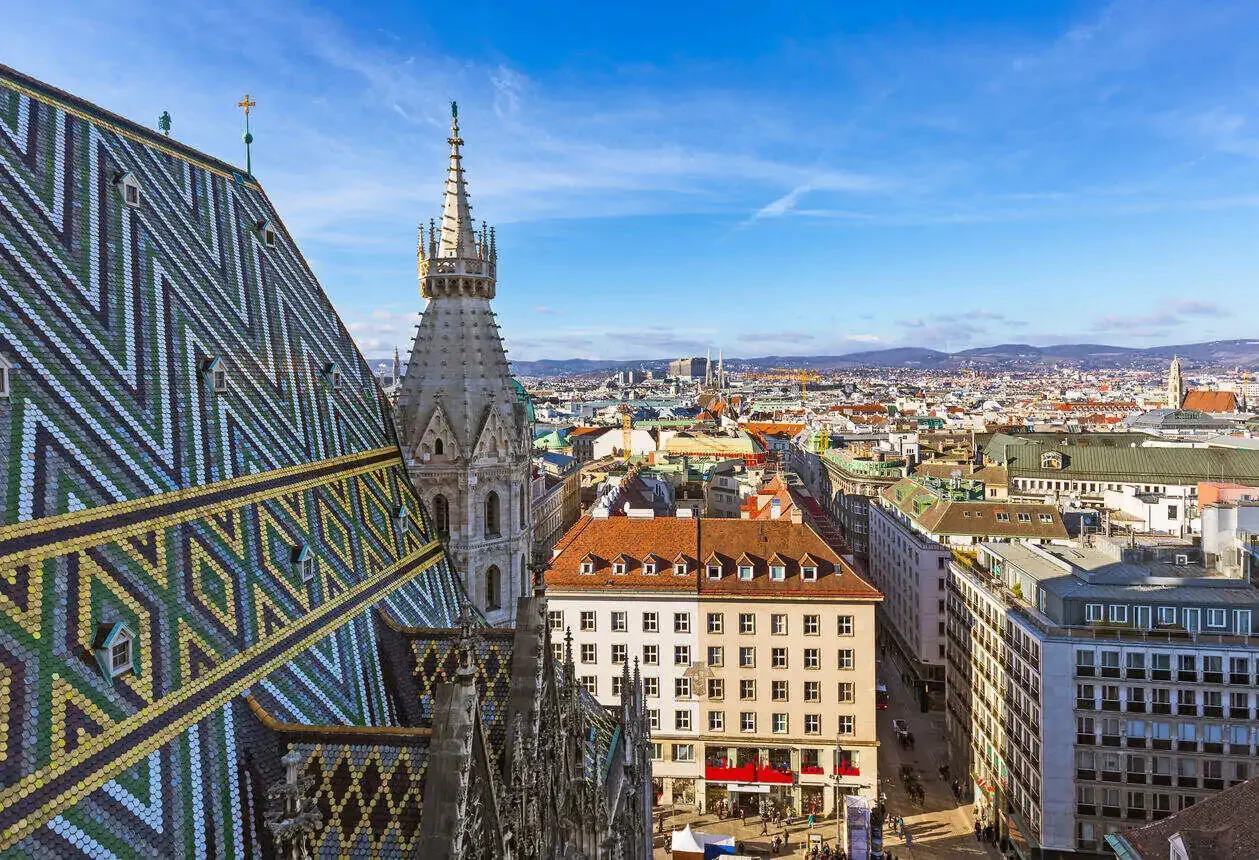 A cathedral's ornately patterned roof and one of its Romanesque towers dominating the city skyline.