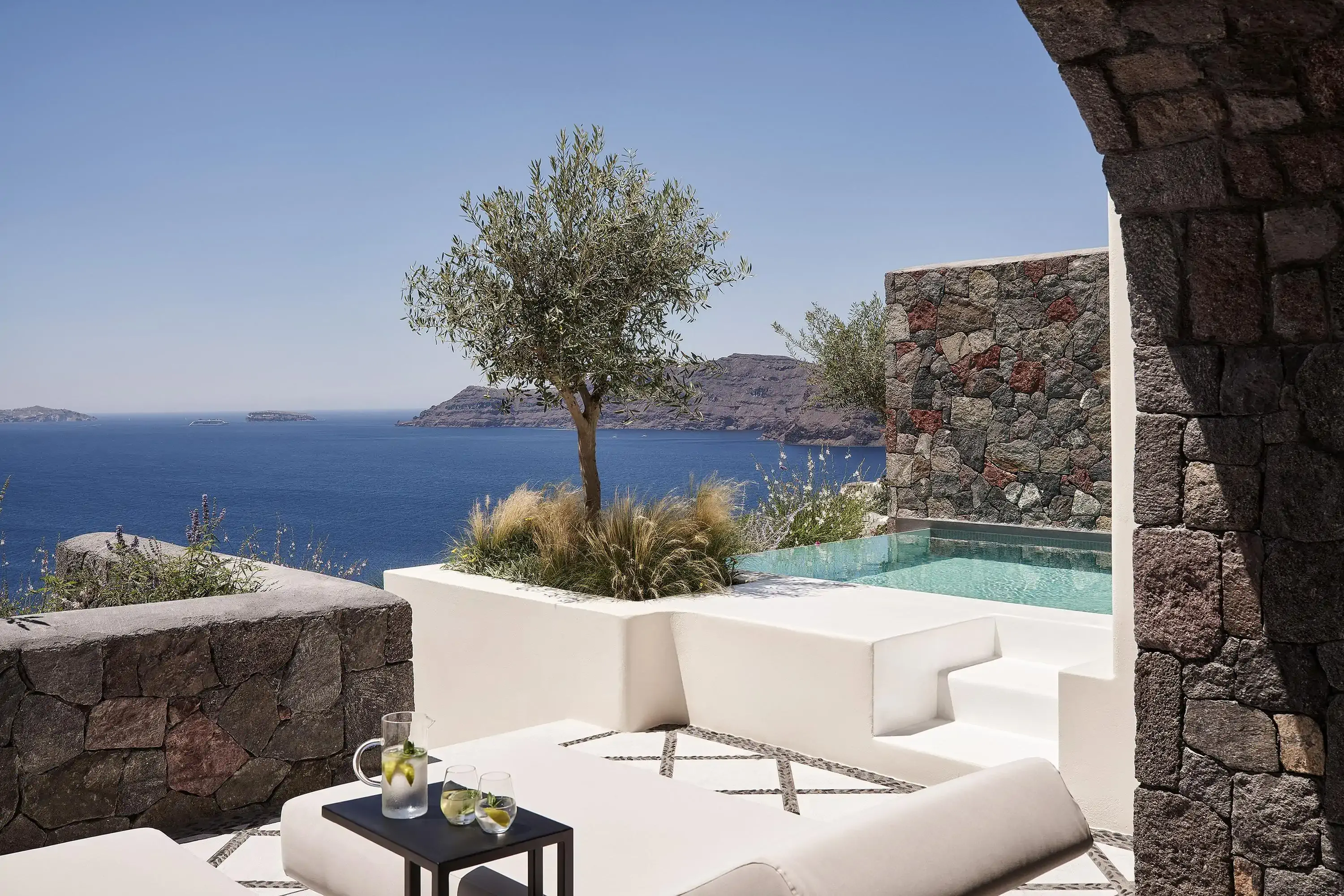 Private patio with modern  garden furniture and private splash pool by an olive tree overlooking a Mediterranean island