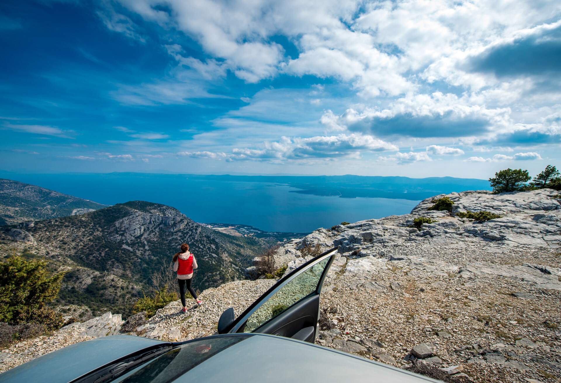 Young woman photographing landscapes near her car on the top of mountain