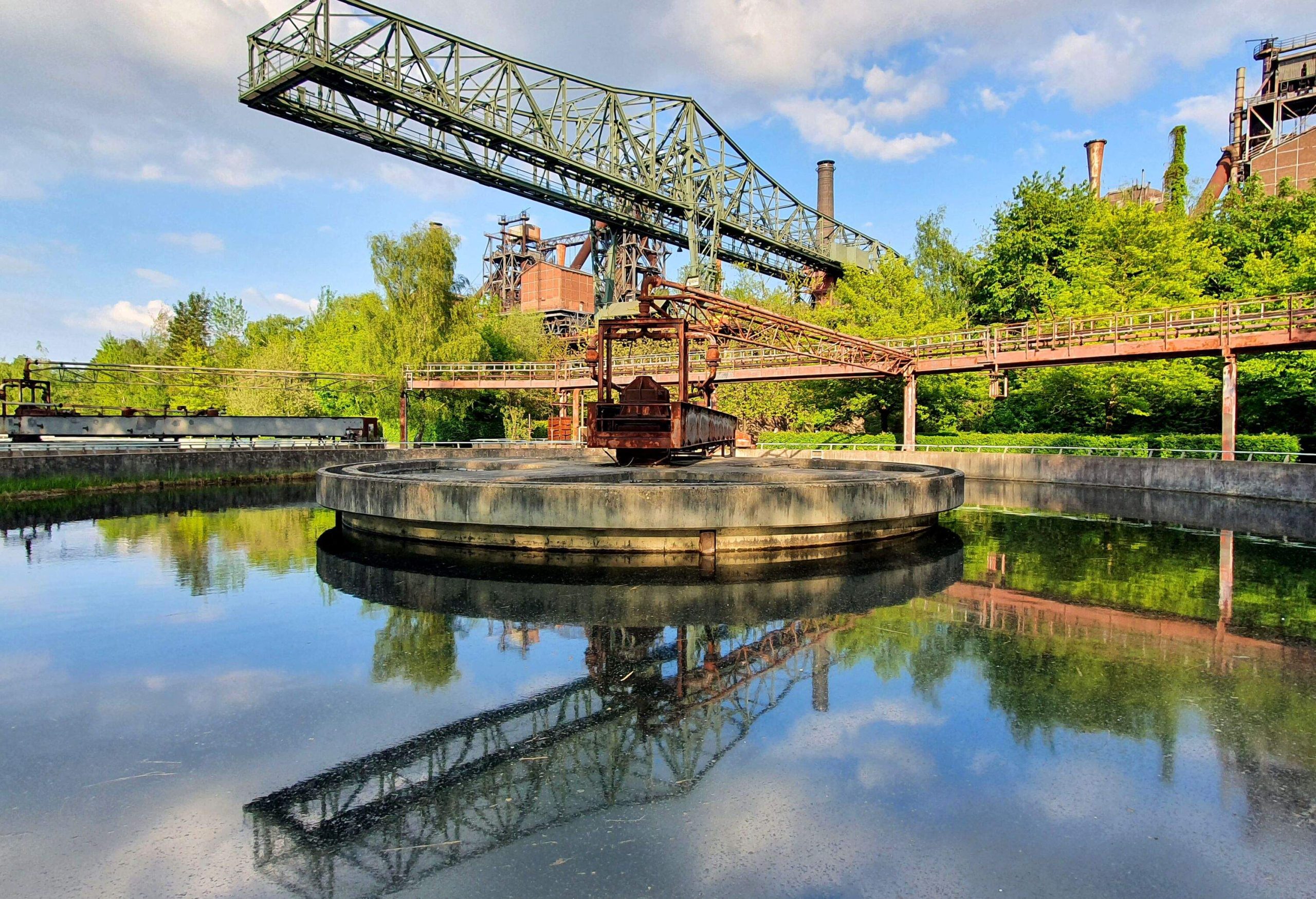 The ore loading bridge (''The crocodile'') with reflection in the clarifier in the Duisburg Landscape Park (Landschaftspark Duisburg-Nord)..The blast furnace complex was built in 1902. It was badly damaged during World War II, but was rebuilt in the 1950s. In 1985 the blast furnaces in the complex was not profitable anymore . and the complex was closed. Between 1991 and 2002 the site was converted into a public park.