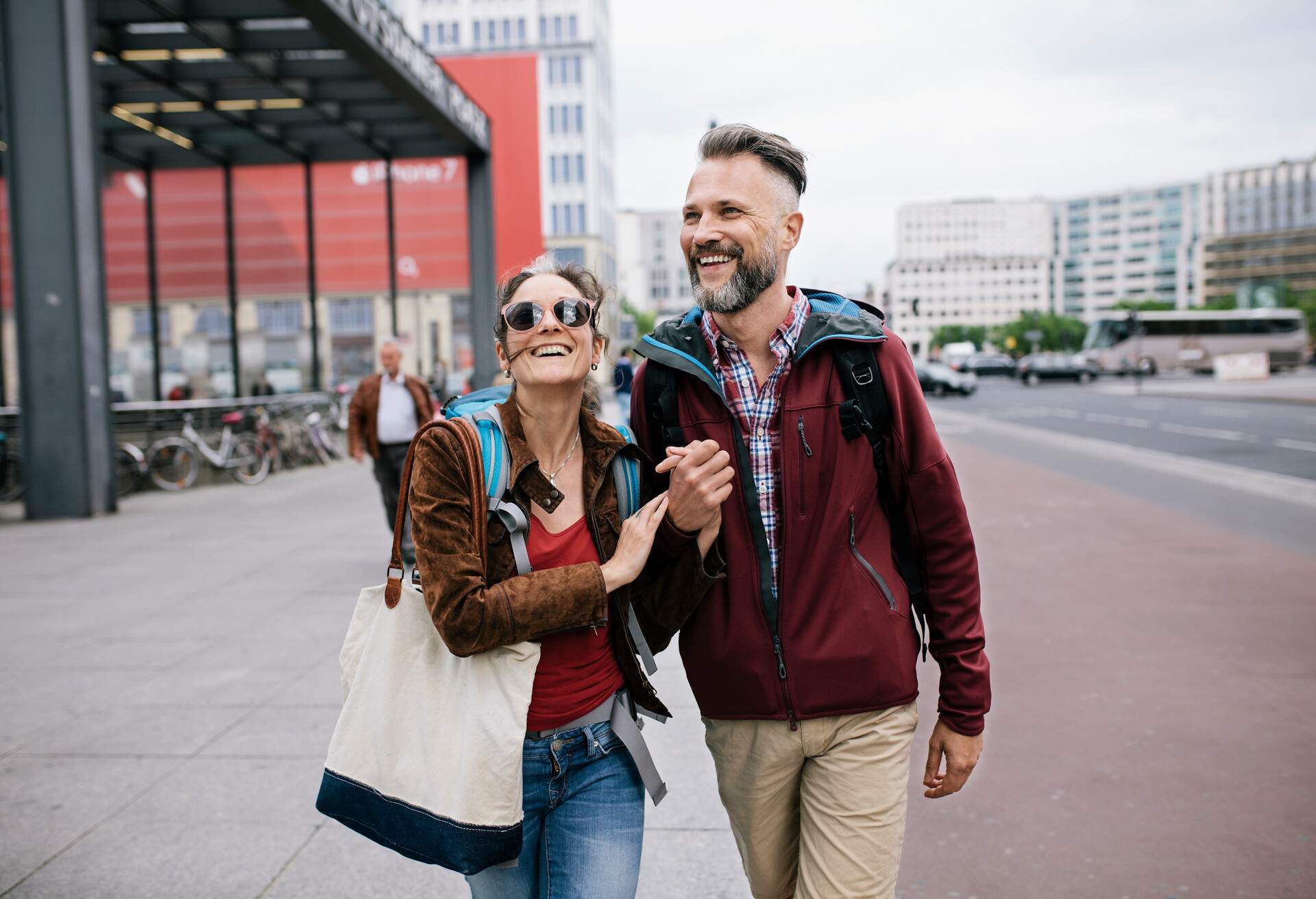 A mature couple are holding hands and smiling as they walk through Berlin together on a day trip.