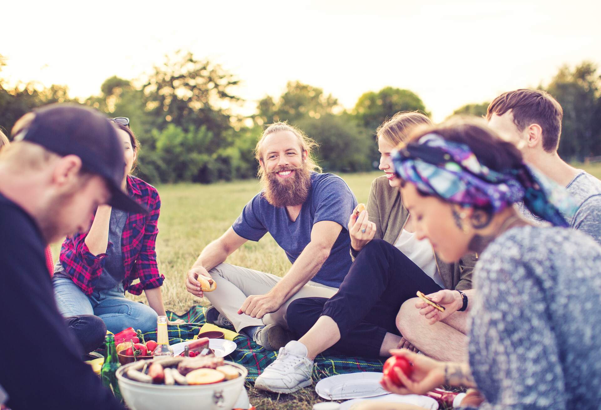 Portrait of handsome young man with friends in park having a picnic