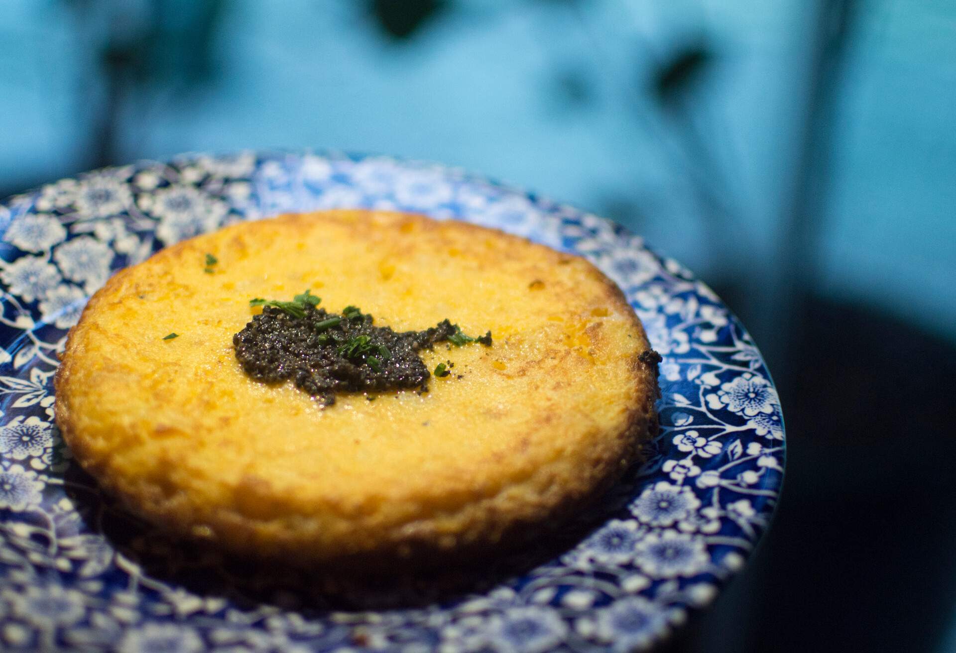 Spanish omelette or Tortilla Espanola, served on a decorative blue floral plate in a restaurant.