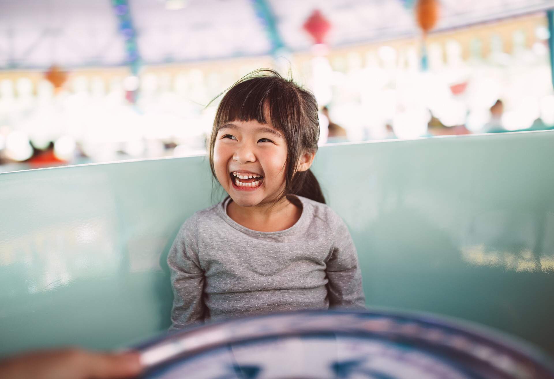 Lovely little girl riding on the amusement park ride joyfully.