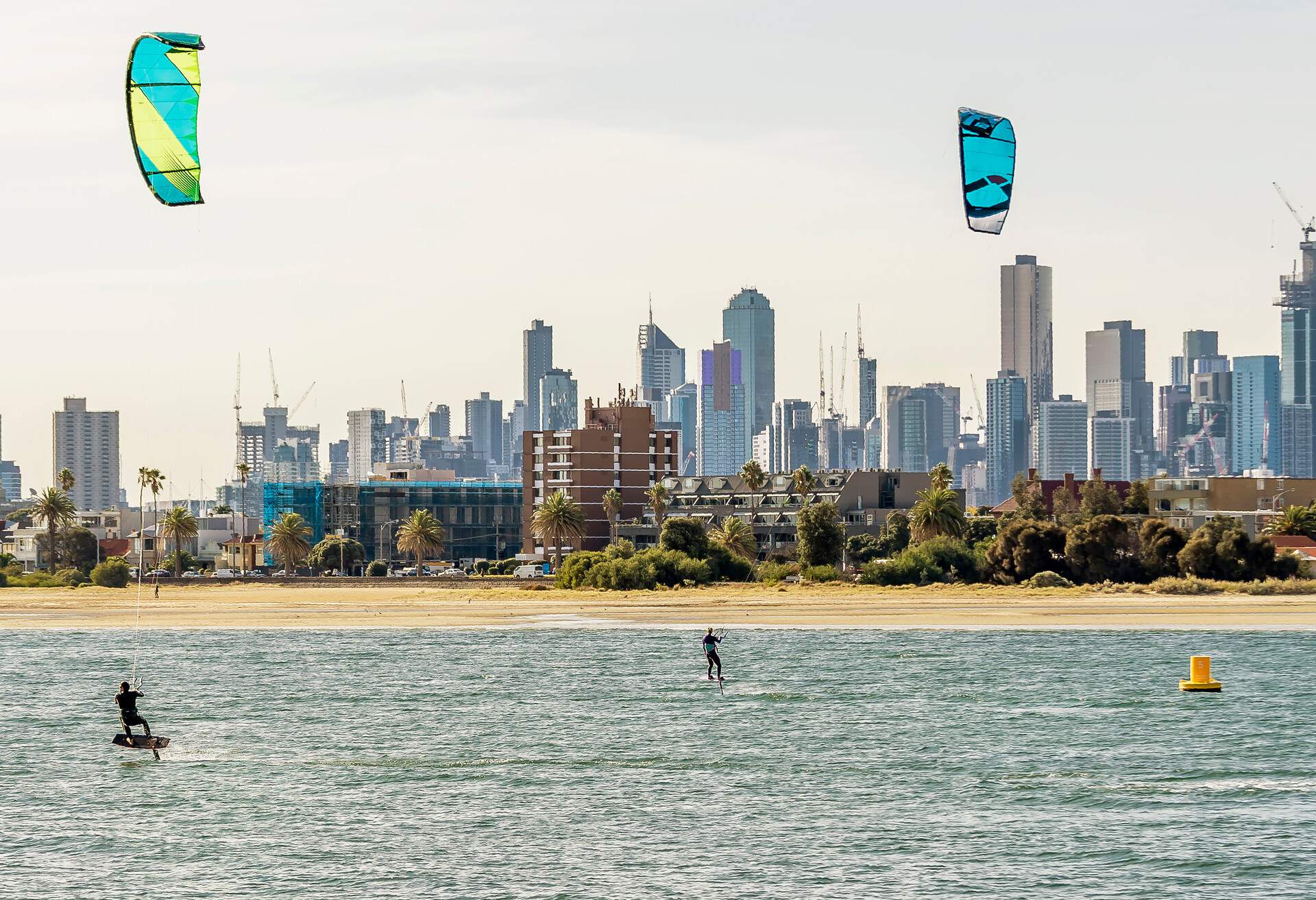 Pair of kitesurfers trains in Port Phillip Bay, with the skyline of Melbourne, Australia in the background.; Shutterstock ID 1461271907