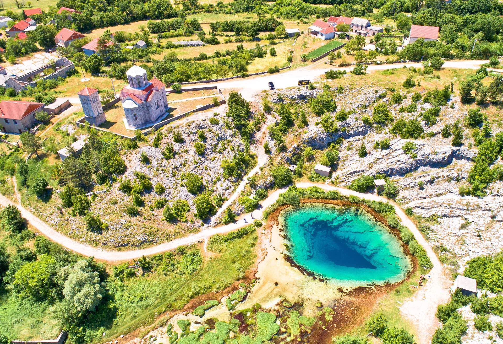 Cetina river source water hole and Orthodox church aerial view, Dalmatian Zagora region of Croatia