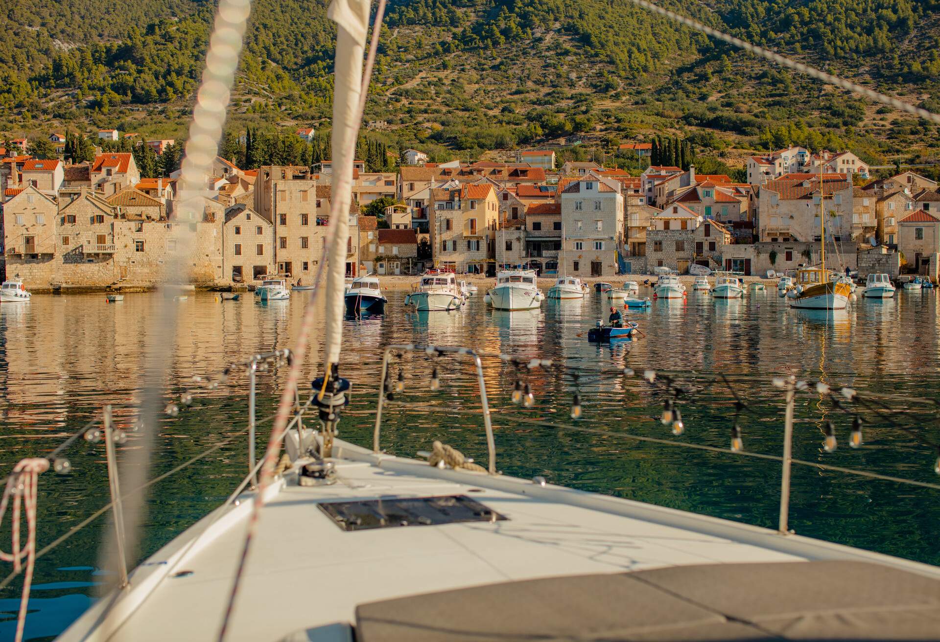 Beautiful village at the waterfront with lots of small buildings, small private and commercial ships and boats standing in front, sailboat with boat deck and railing in front