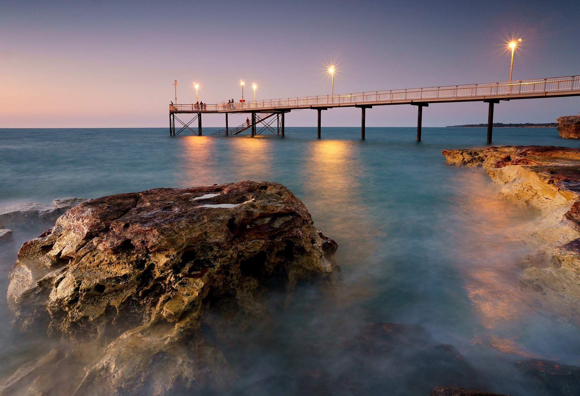 Sunset at Nightcliff Jetty in Darwin Northern Territory Australia during high tide with rocks surrounded by water.