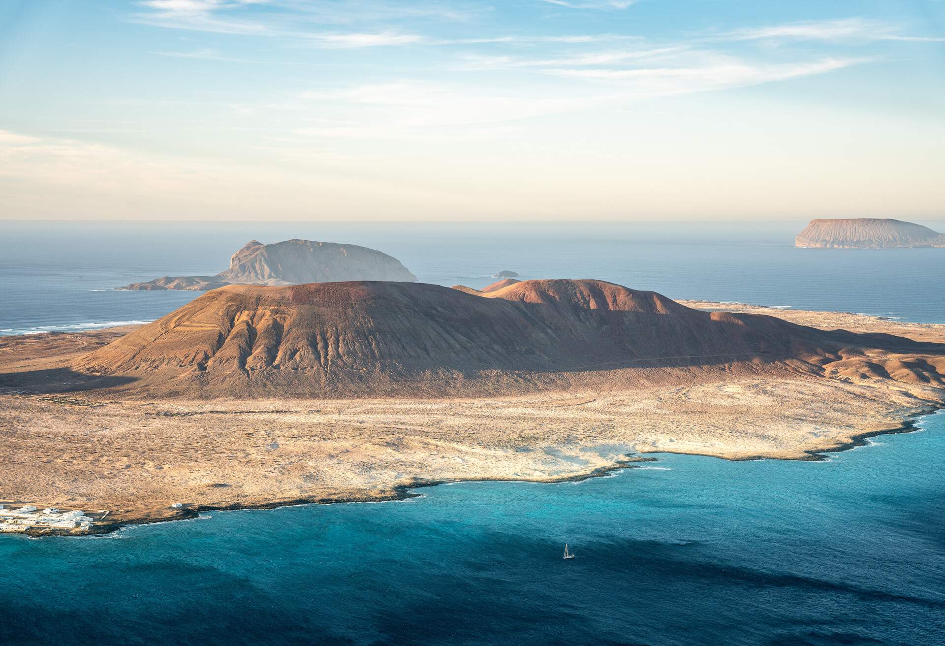 A volcanic island with sandy beaches against deep blue waters of the sea.