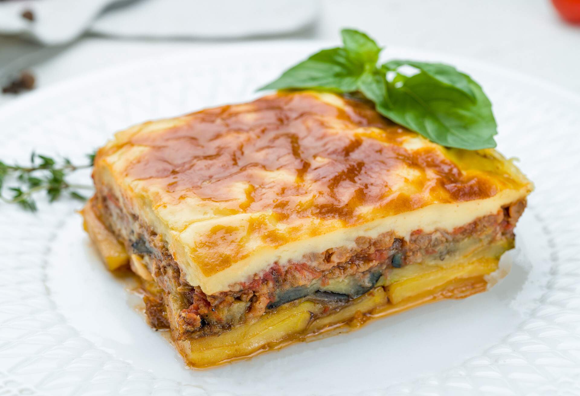 Eggplant moussaka Greek cuisine on white plate on white concrete table