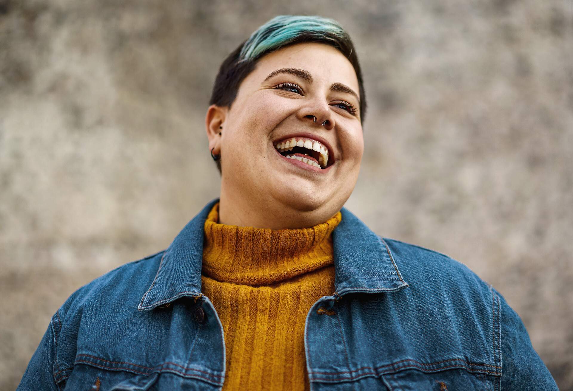 A young woman of non-binary sexuality smiles showing her teeth