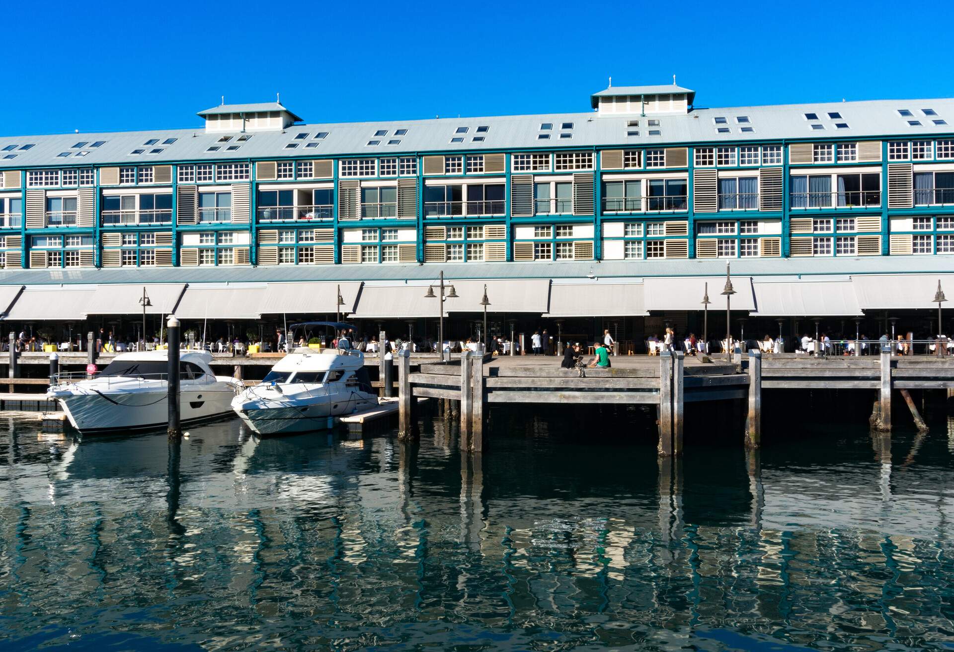 Finger wharf restaurants and hotel in Woolloomooloo bay with unrecognisable people in the distance. Sydney, Australia