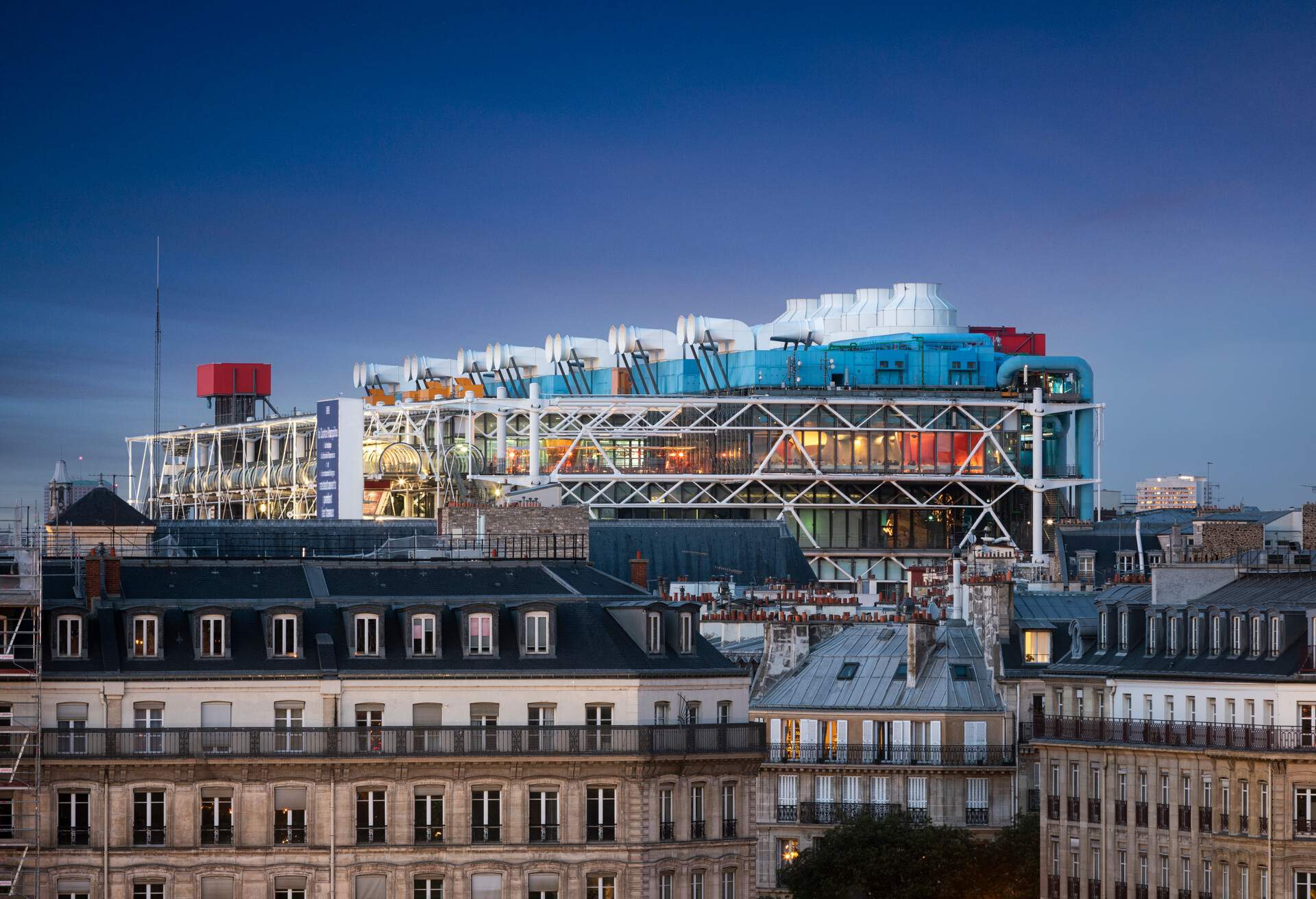 An evening shot of the colourful and industrial building of the museum of Pompidou in the middle of Paris with french apartment buildings in front