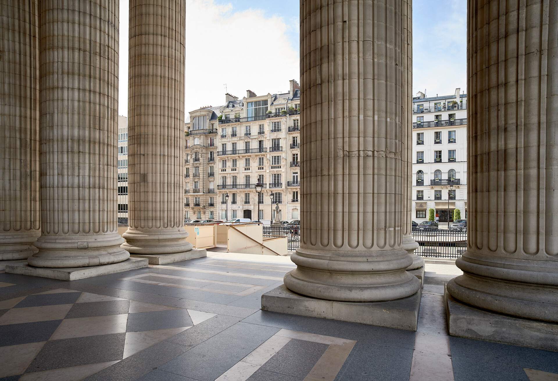 A look at some french haussmannian buildings through some big columns at the Pantheon in Paris 