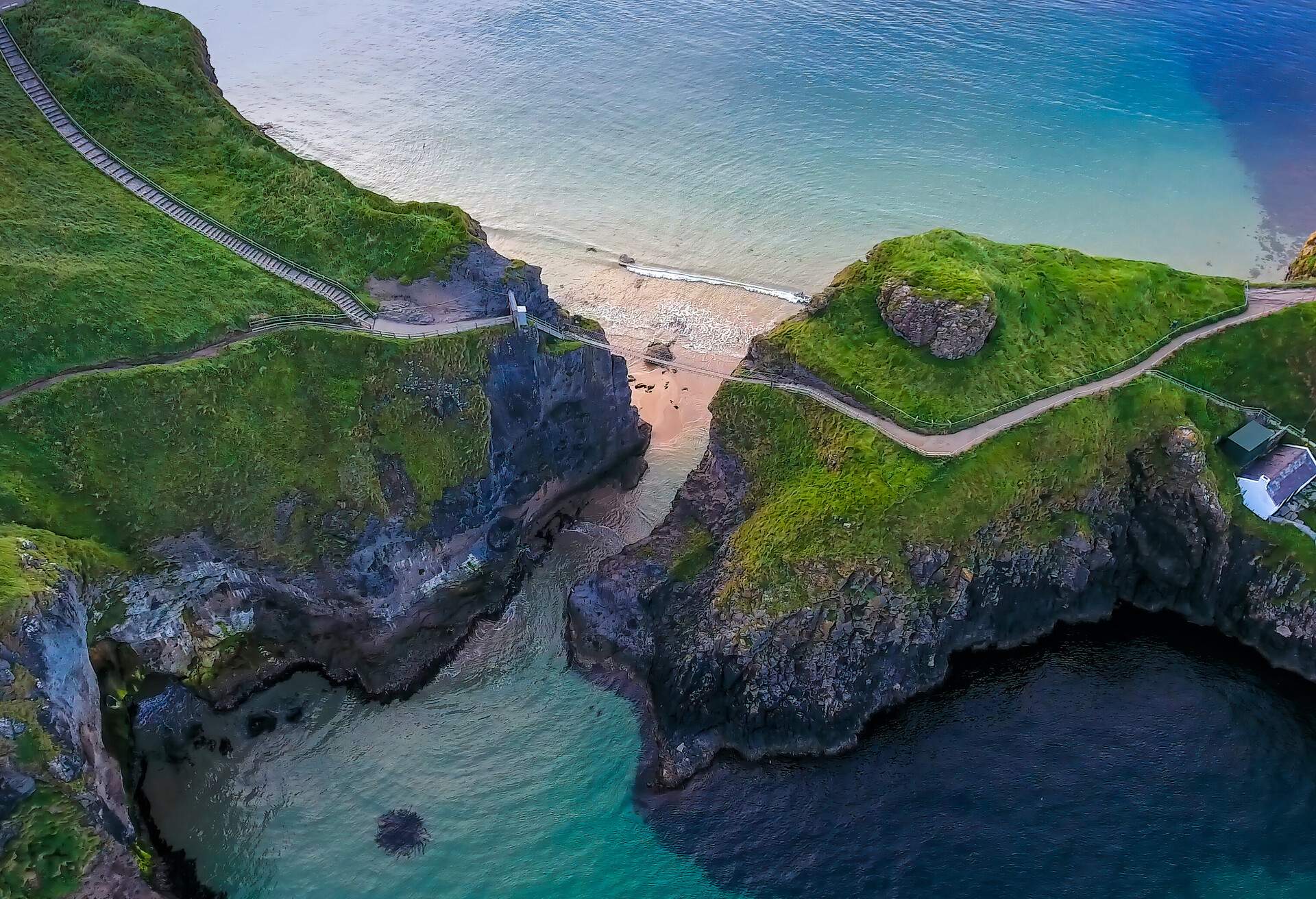 The rope bridge connecting the two cliffs in Northern Ireland it is called the Carrick-a-Rede Rope Bridge taken in an aerial shot