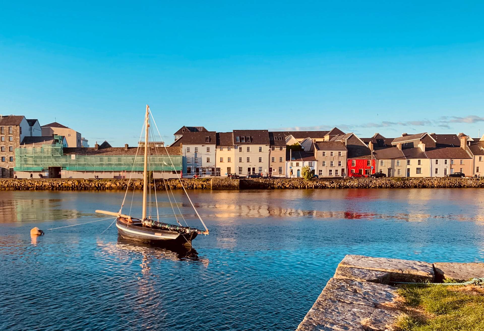 A boat in the bay at Claddagh, Galway, Ireland on a summers day with the colorful houses in the background