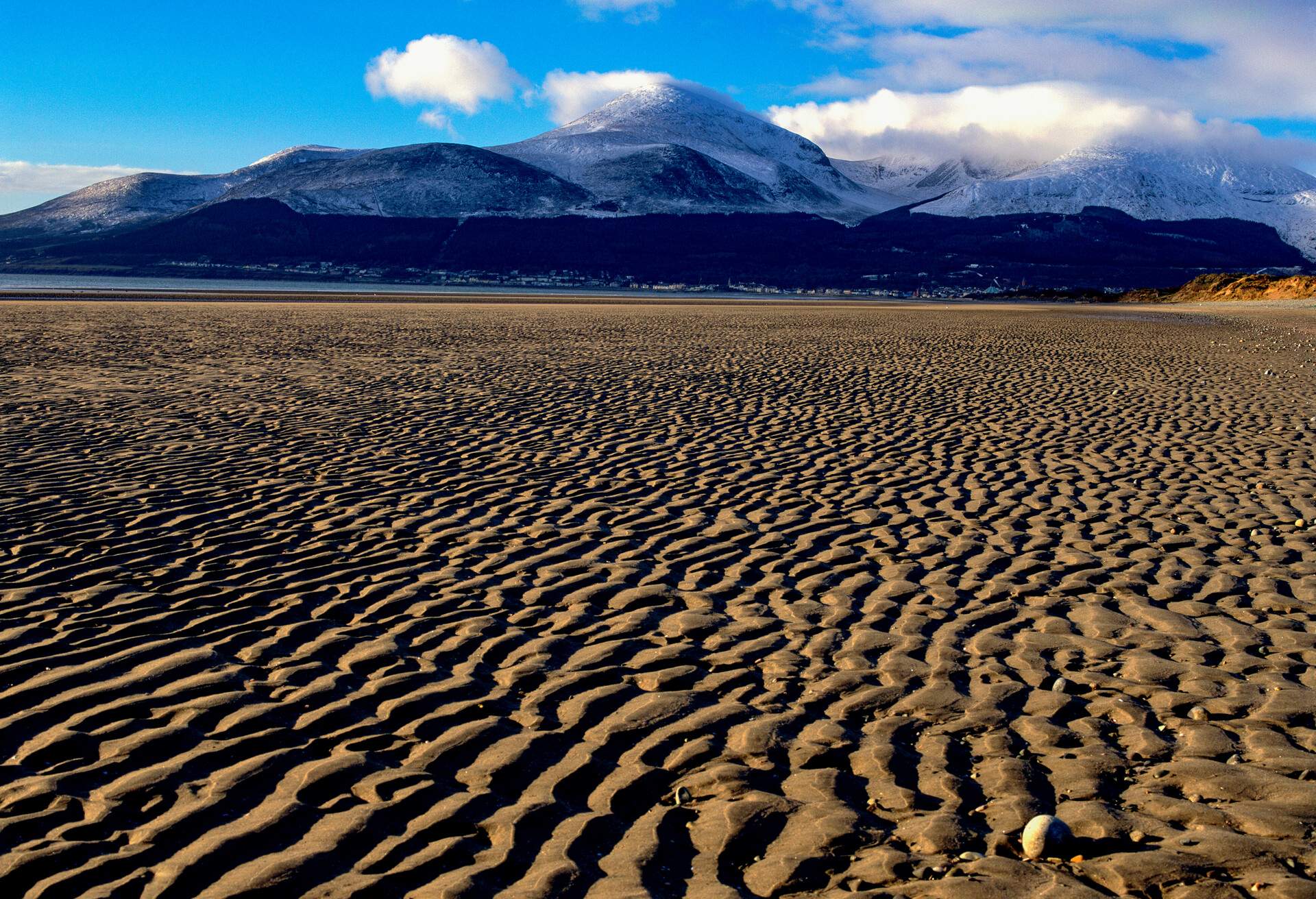 Ripples in the sand on Murlough Beach, Newcastle, County Down, Northern Ireland. In the background the Mourne Mountains have a light covering of snow