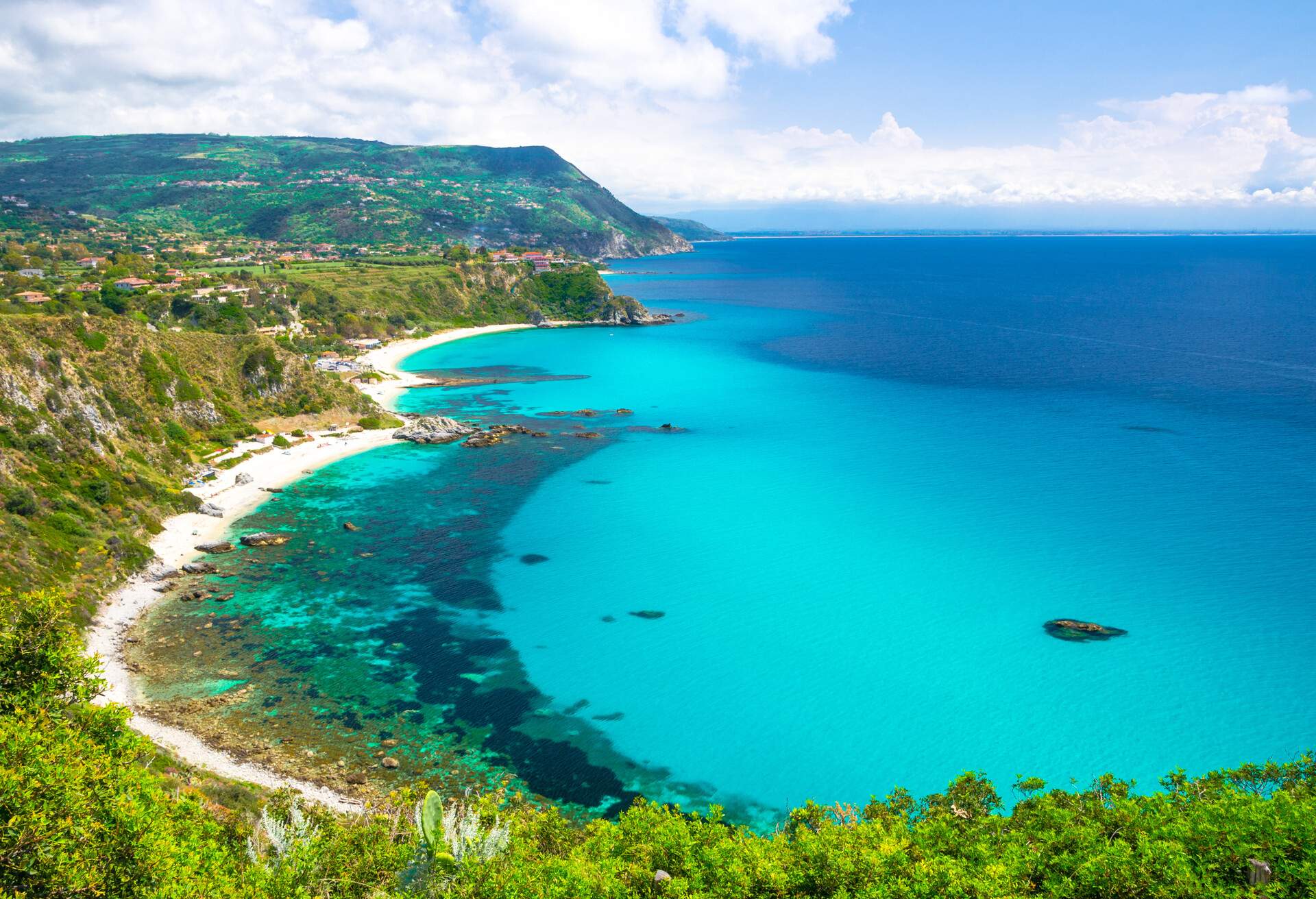 Aerial amazing tropical view of turquoise gulf bay, sandy beach, green mountains and plants, blue sky white clouds background from cliffs platform Cape Capo Vaticano Ricadi, Calabria, Southern Italy; Shutterstock ID 1161360646