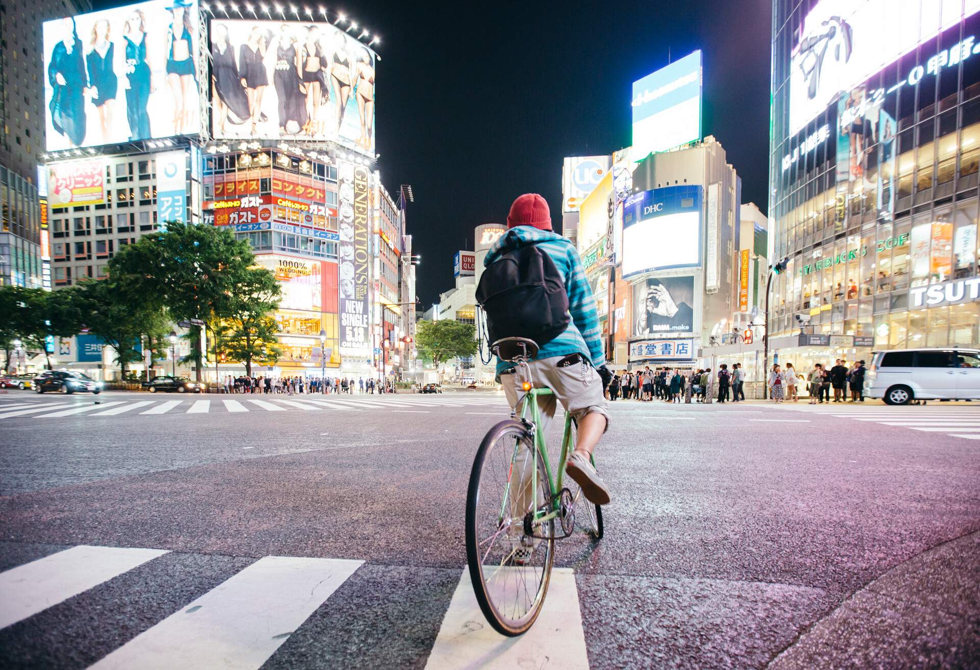 Young guy with backpack riding a bike on Shibuya crossing in Tokyo, Japan