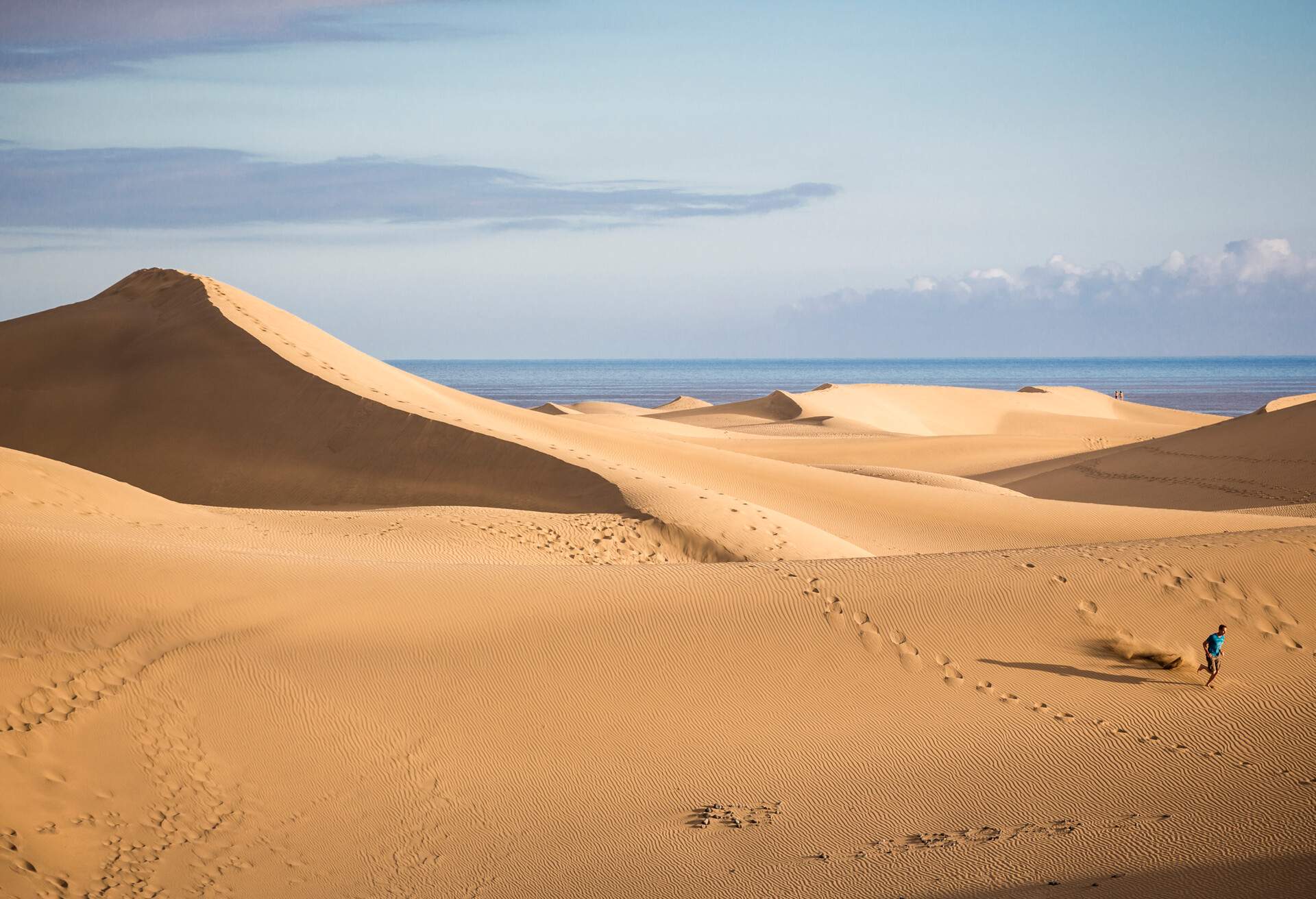 A man running down the sand dune slopes.