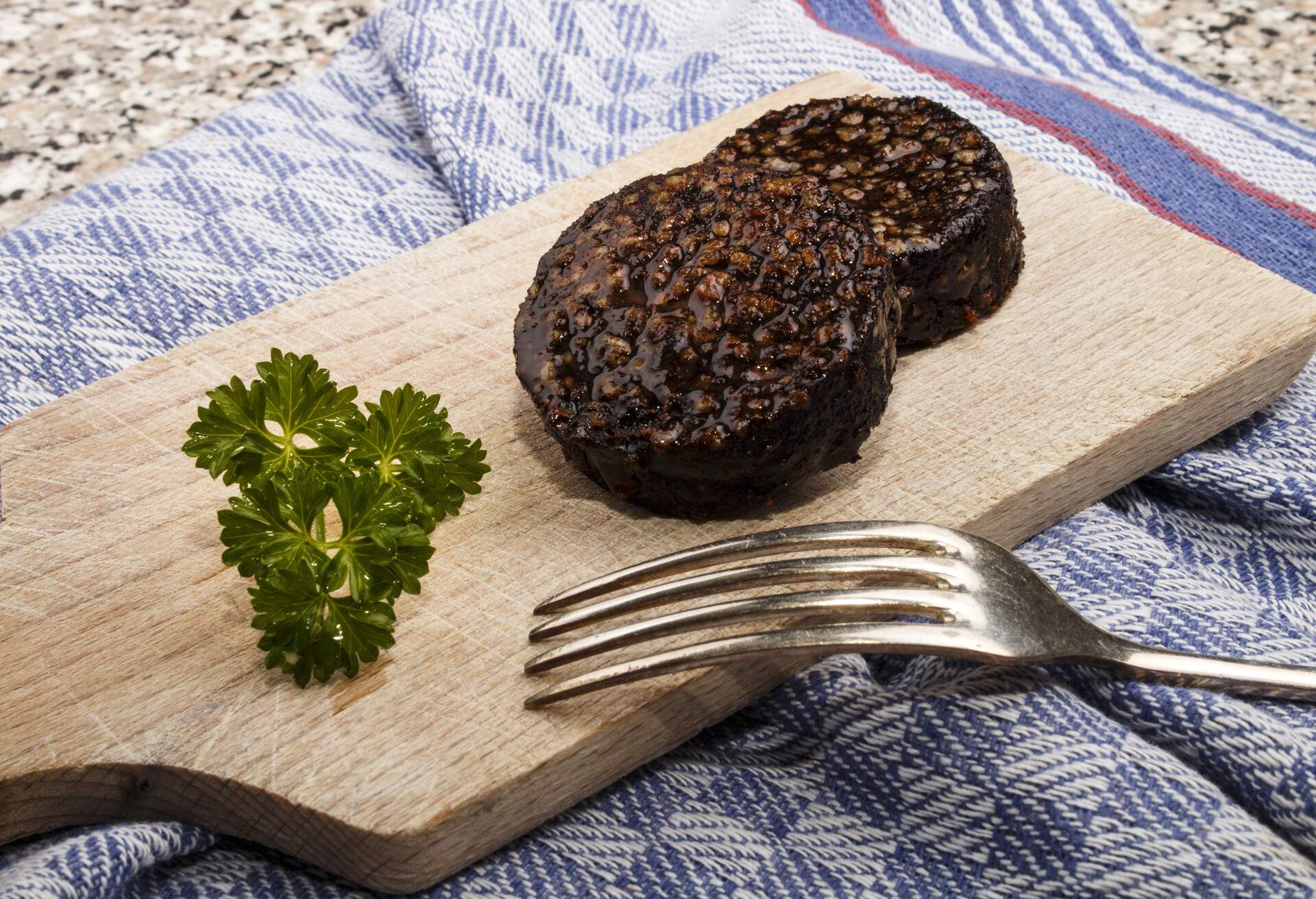 grilled irish black pudding made with oatmeal on a wooden board with knife and parsley