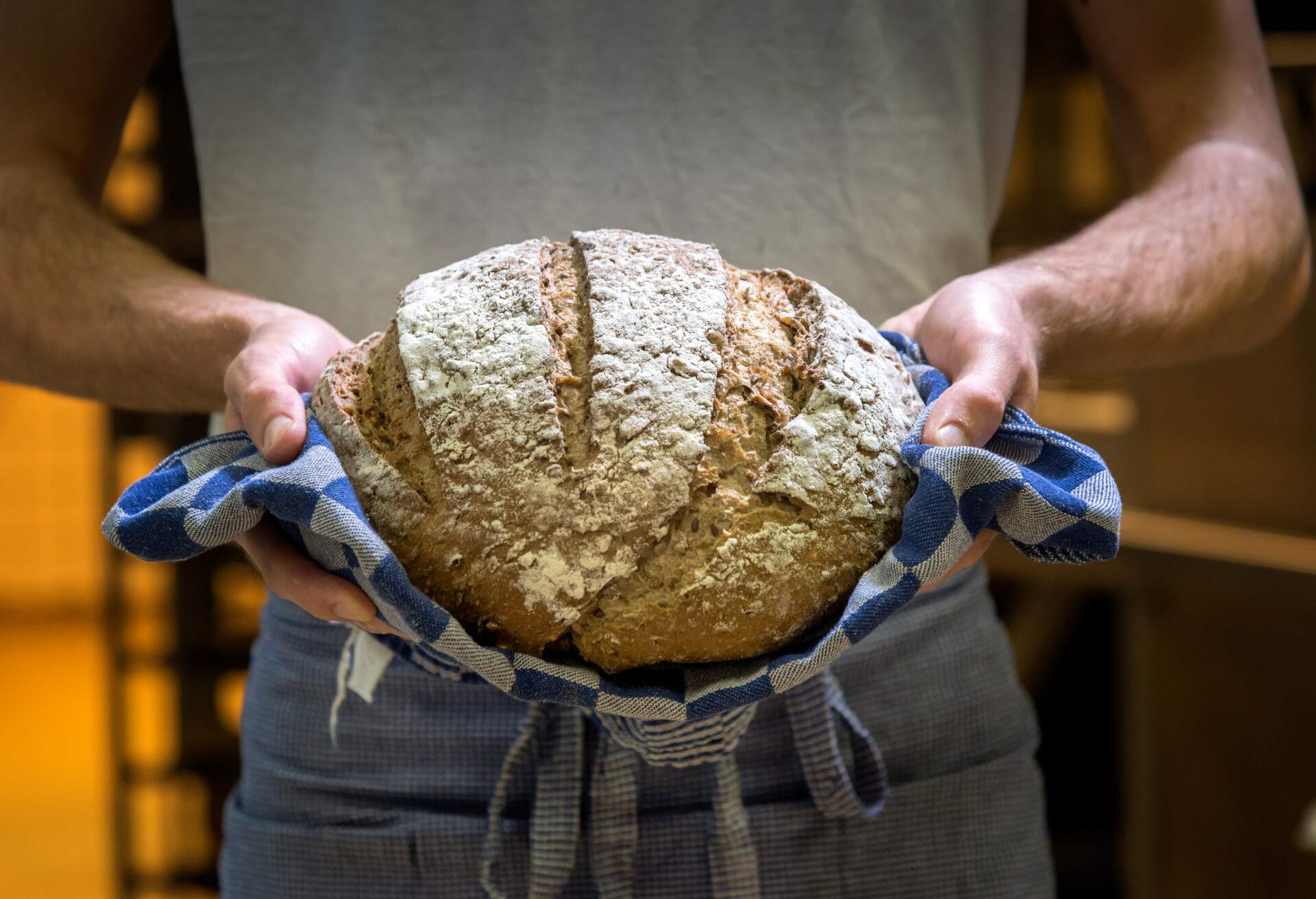 Baker shot in bakery, with warm bread just out of the oven