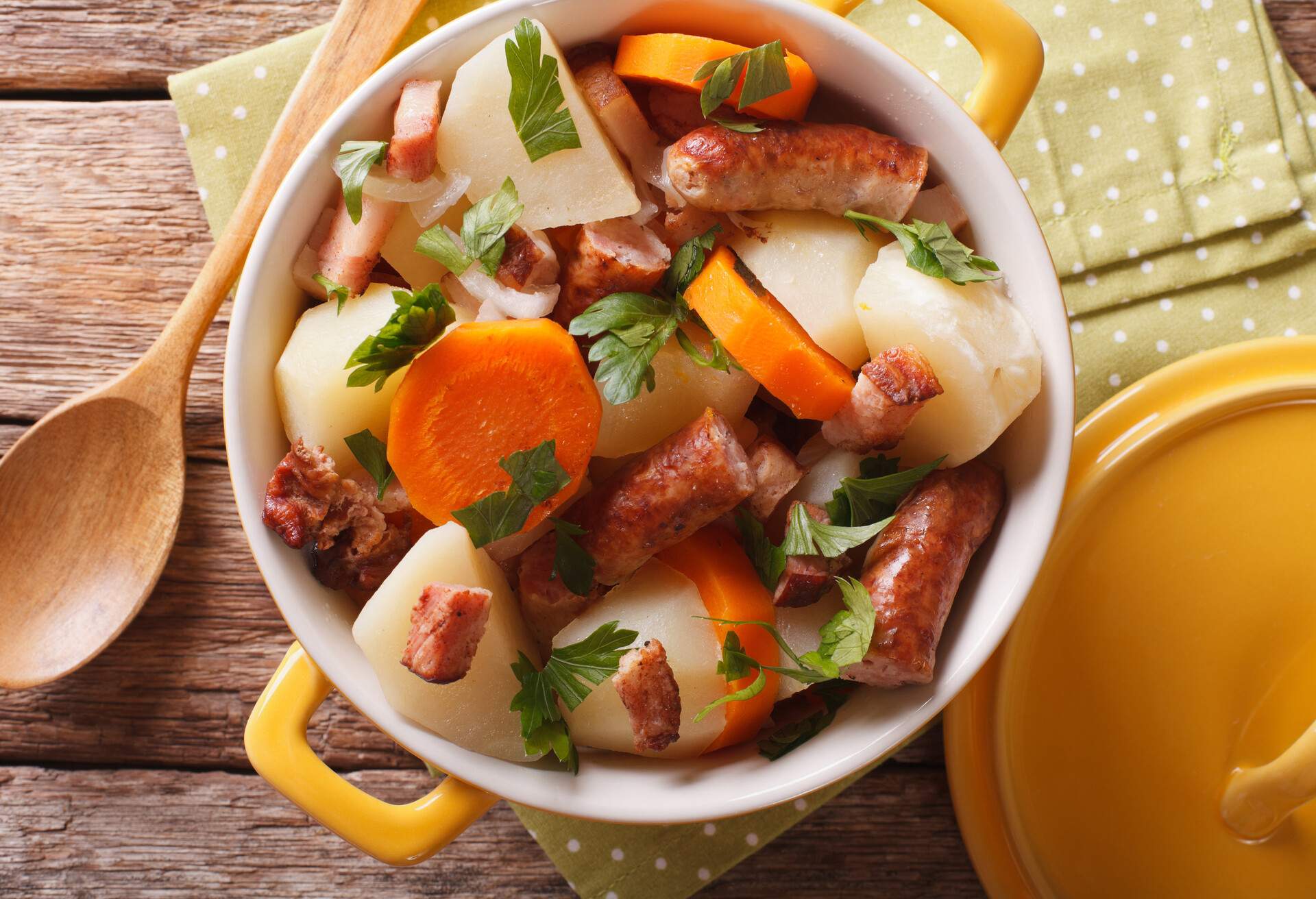 Portion of the Dublin coddle close-up in yellow pot on the table. Horizontal view from above