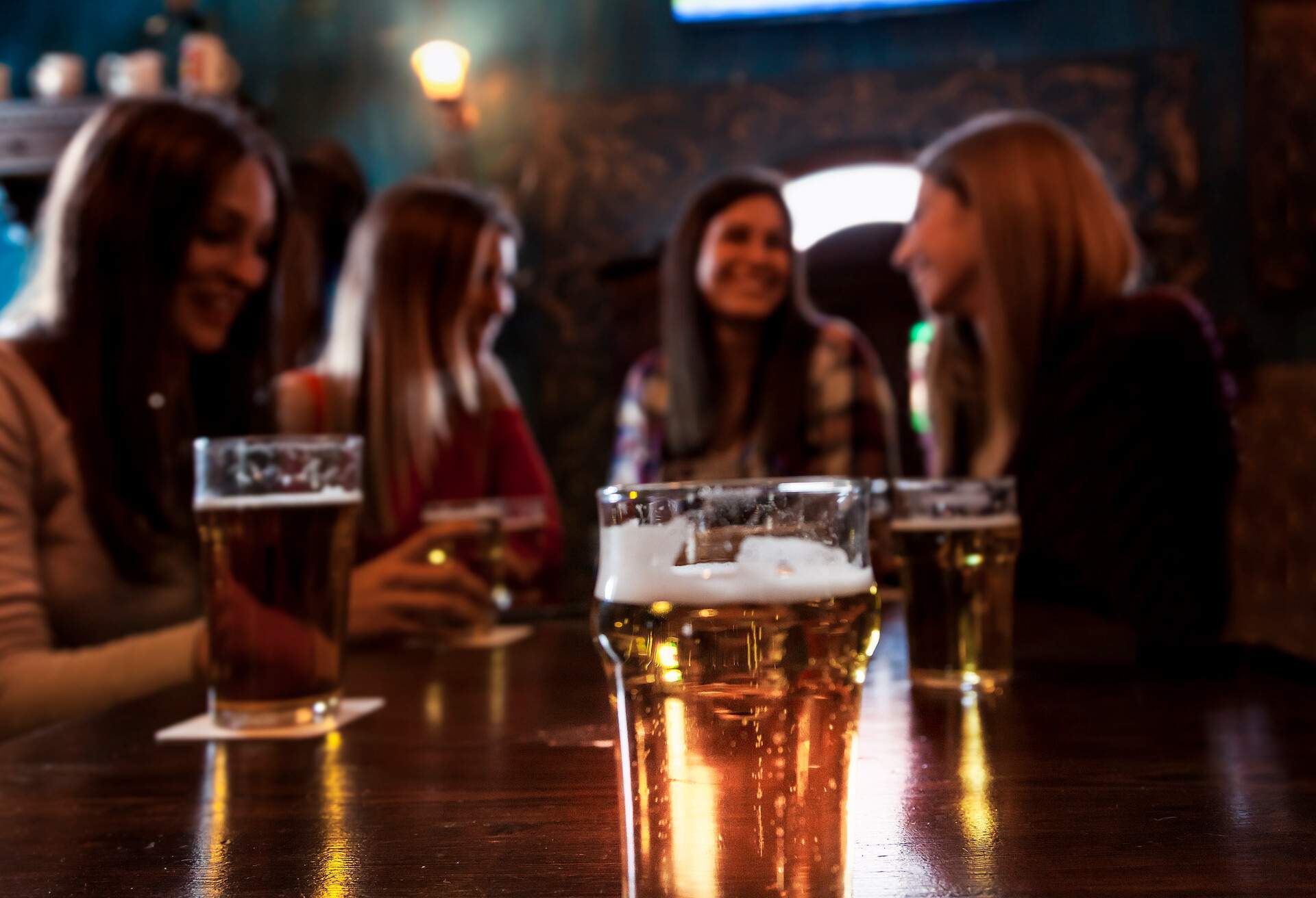group of millennial women having fun drinking beer in a pub